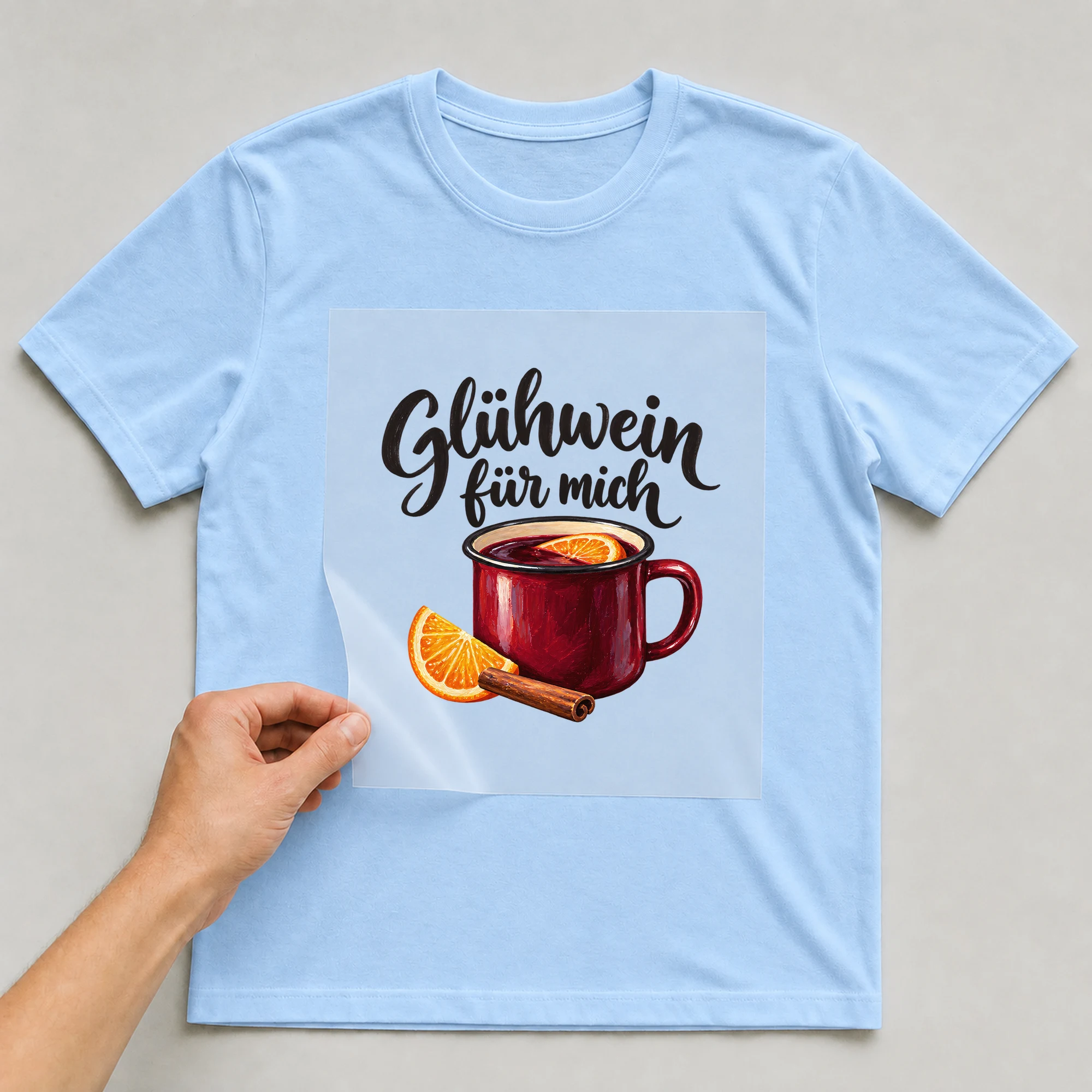 Bügelbild „Glühwein für mich“ auf babyblauem T-Shirt, Folie wird aufgelegt