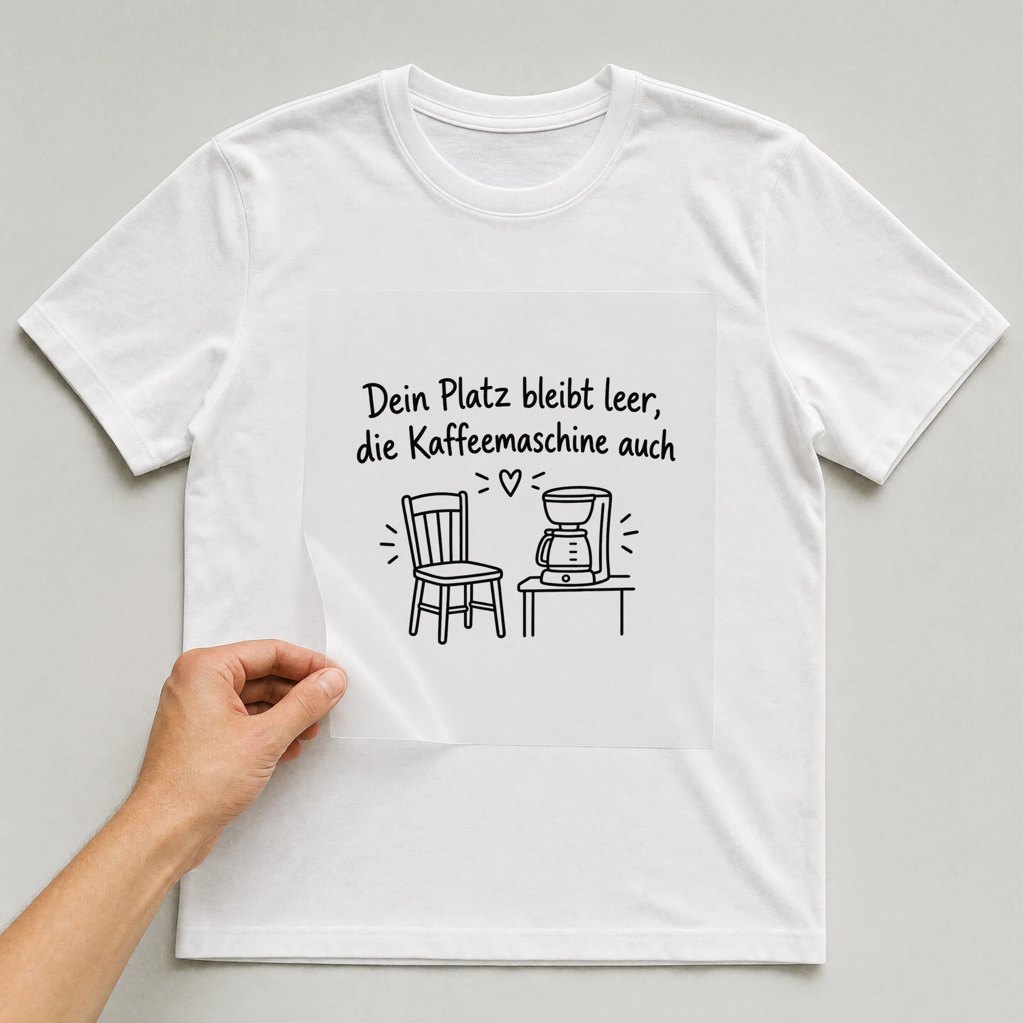 Bügelbild „Dein Platz bleibt leer, die Kaffeemaschine auch“ auf weißem T-Shirt, Folie wird aufgelegt