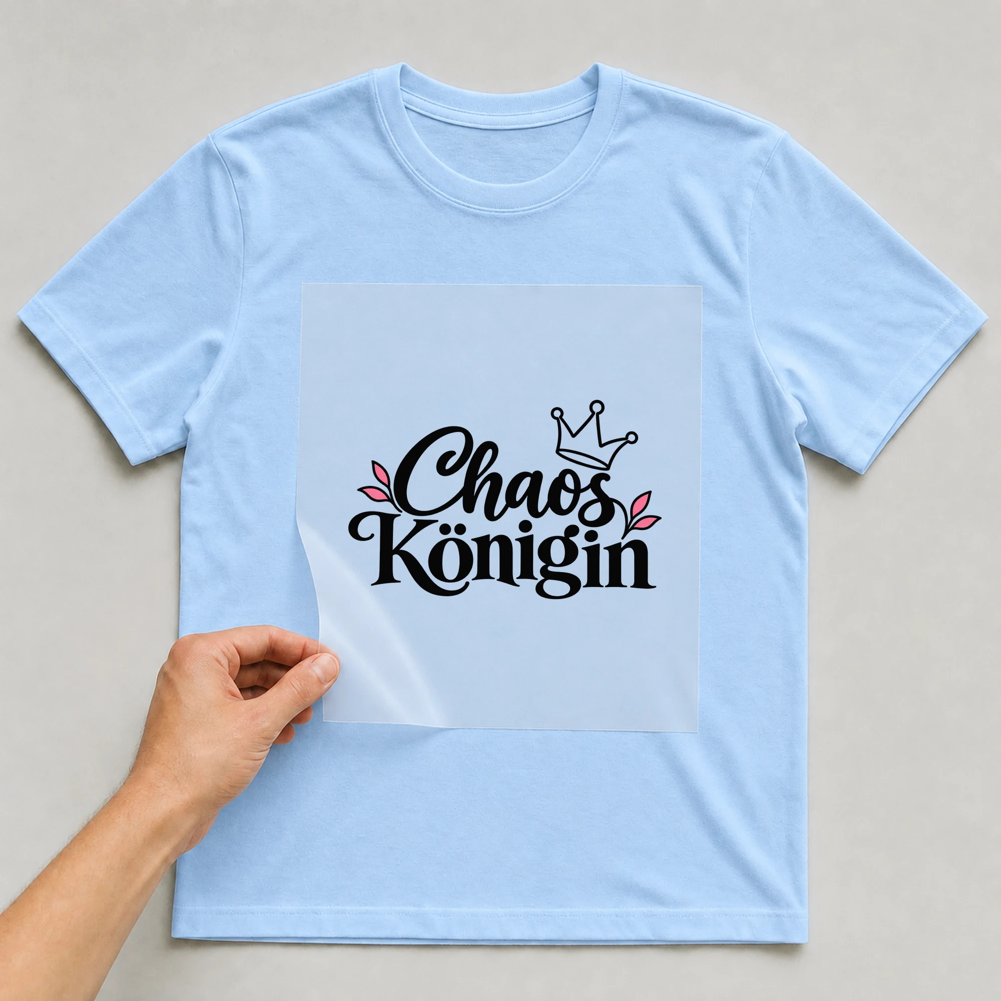 Bügelbild „Chaos Königin“ auf babyblauem T-Shirt, Folie wird aufgelegt