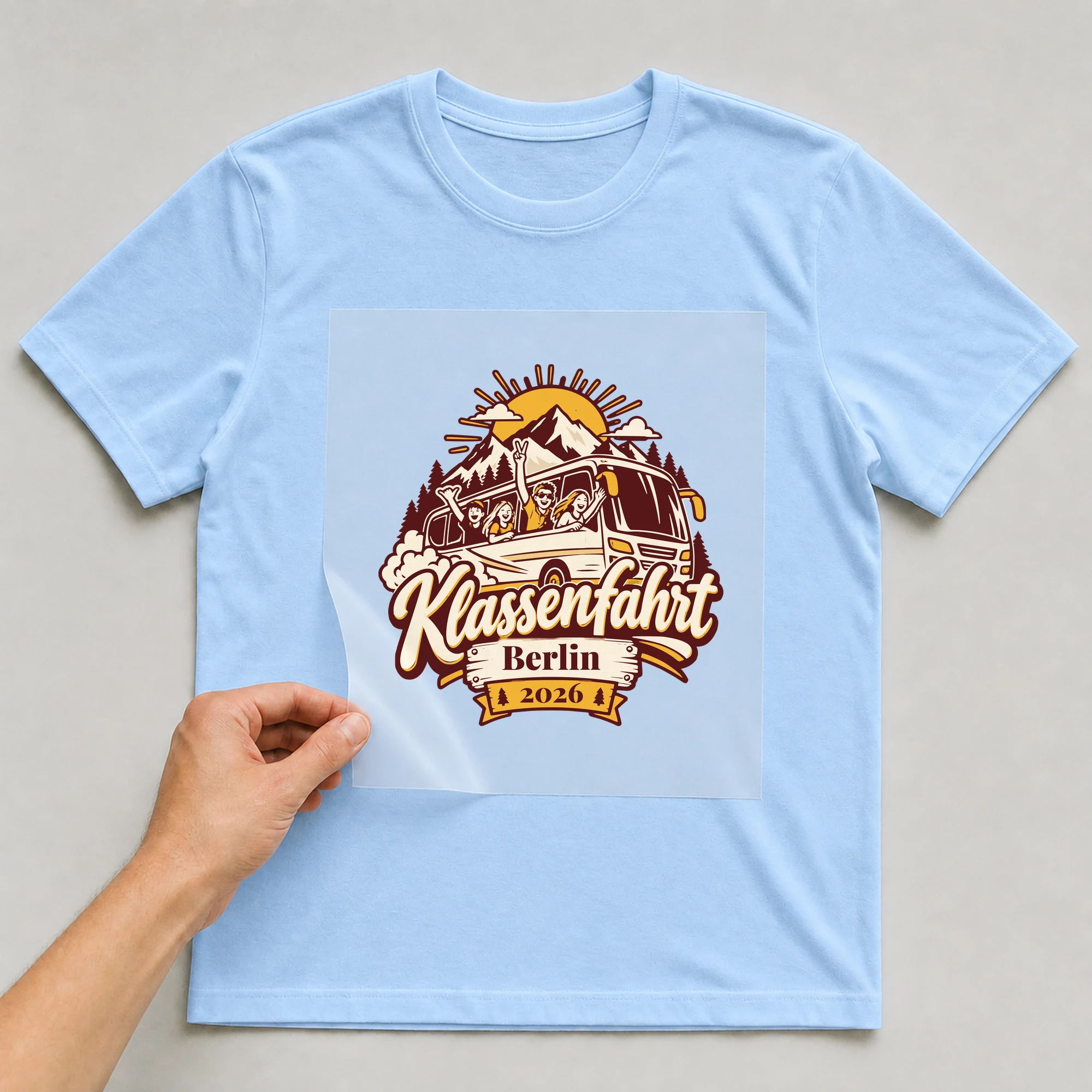 Bügelbild Klassenfahrt mit Ort und Jahr auf hellblauem T-Shirt, Folie wird aufgelegt