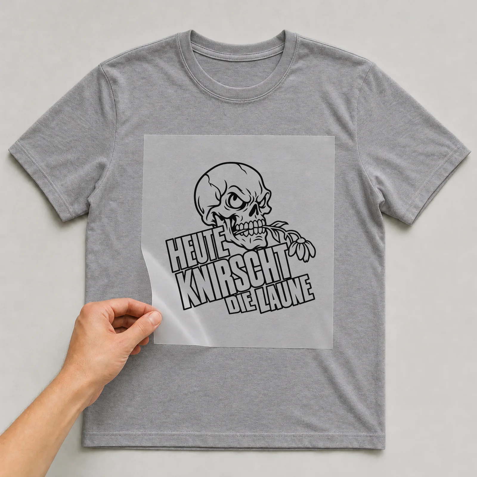Bügelbild „Heute knirscht die Laune“ auf grauem T-Shirt, Folie wird aufgelegt