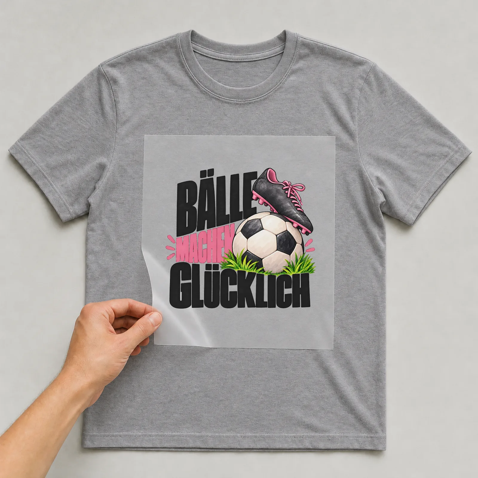 Bügelbild „Bälle machen glücklich“ auf grauem T-Shirt, Folie wird aufgelegt