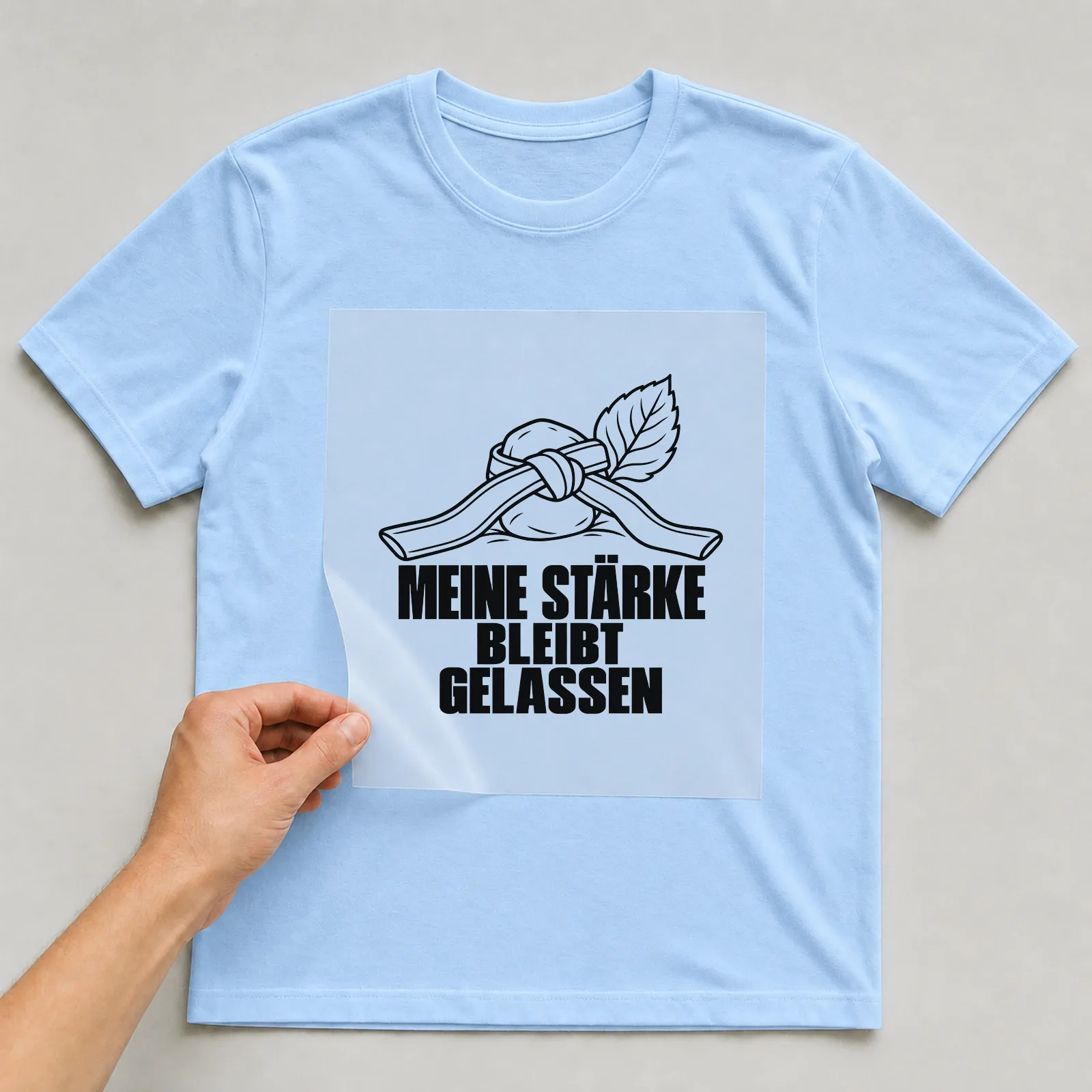 Bügelbild „Meine Stärke bleibt gelassen“ auf hellblauem T-Shirt, Folie wird aufgelegt