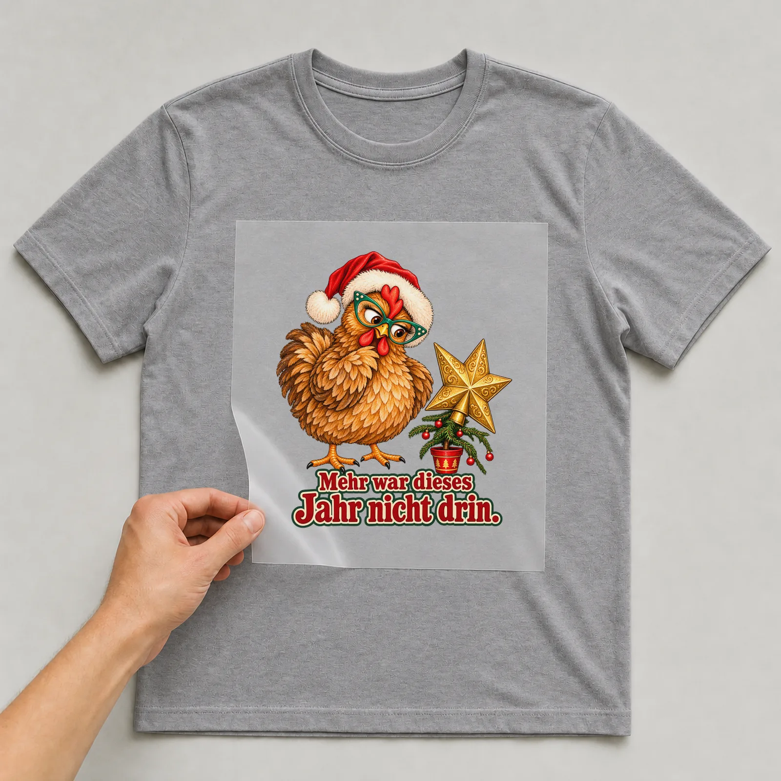 Bügelbild huhn mini tannenbaum auf grauem T-Shirt, Folie wird aufgelegt