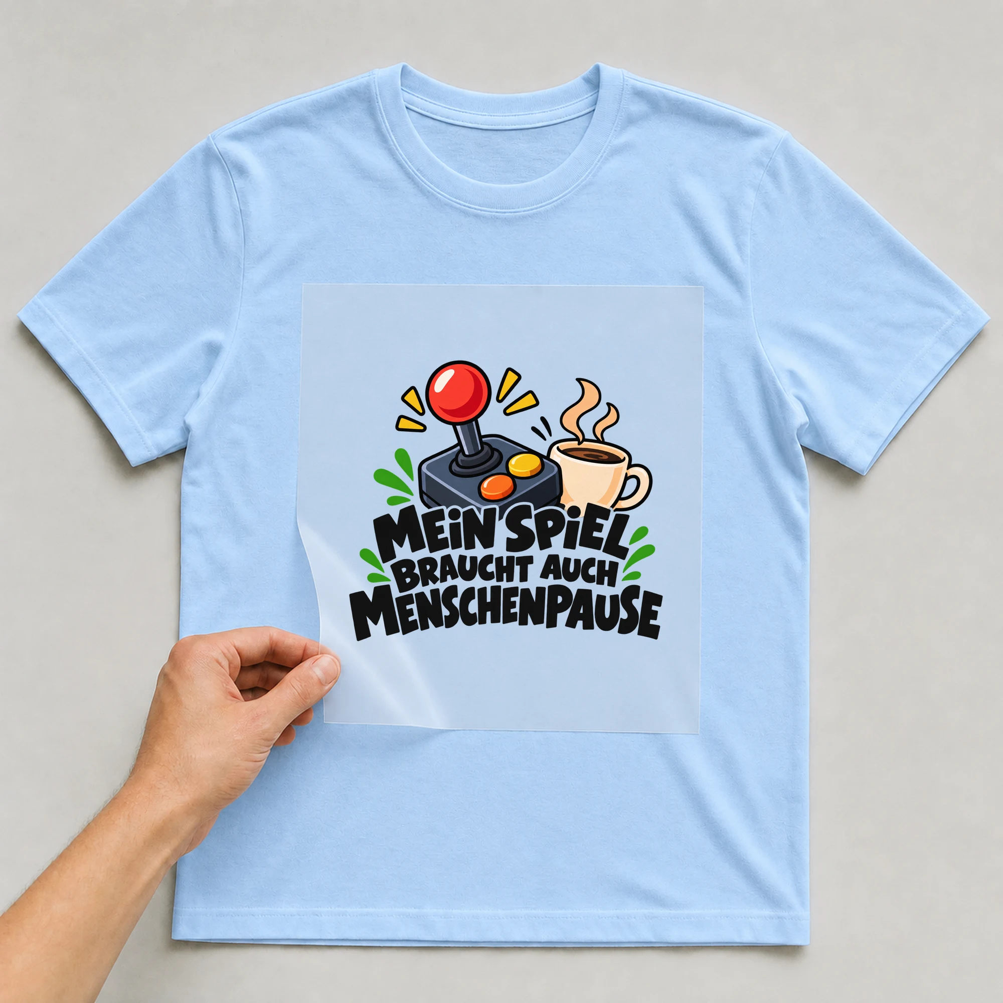 Bügelbild „Mein spiel braucht auch Menschenpause“ auf hellblauem T-Shirt, Folie wird aufgelegt