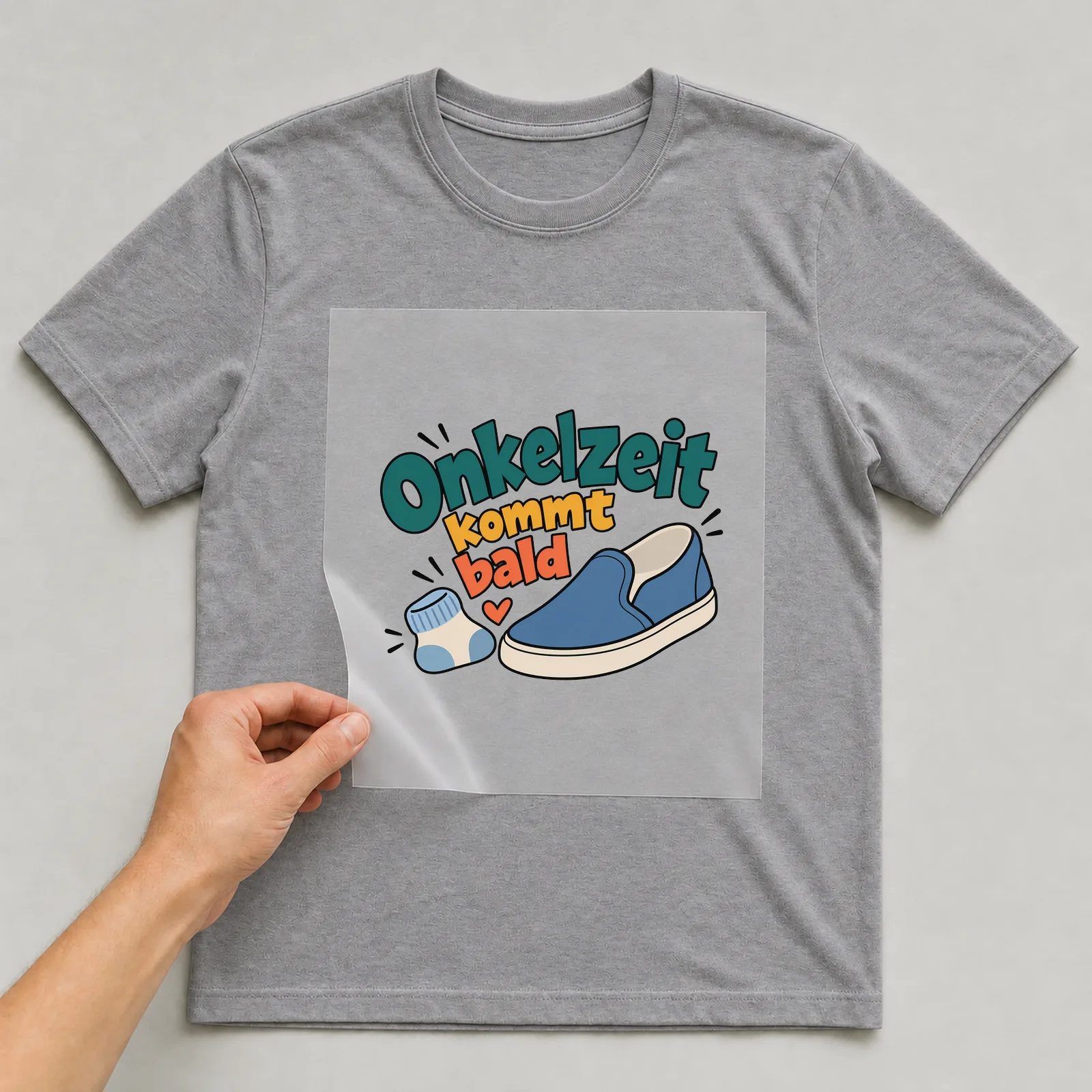 Bügelbild „Onkelzeit kommt bald“ auf grauem T-Shirt, Folie wird aufgelegt