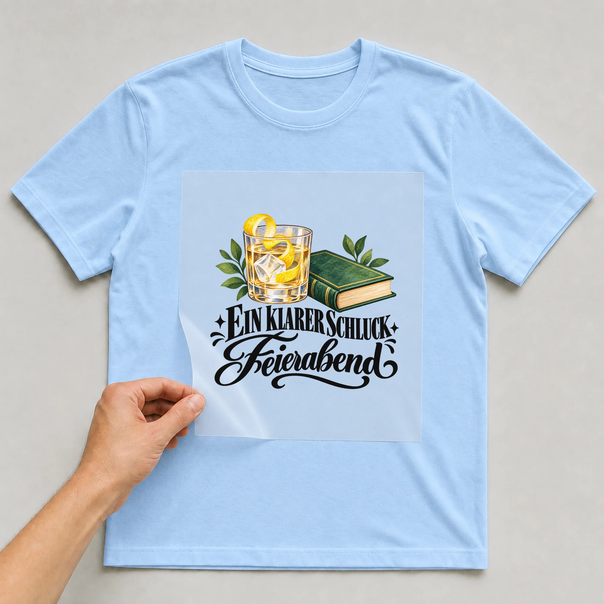 Bügelbild „Ein klarer Schluck Feierabend“ auf babyblauem T-Shirt, Folie wird aufgelegt