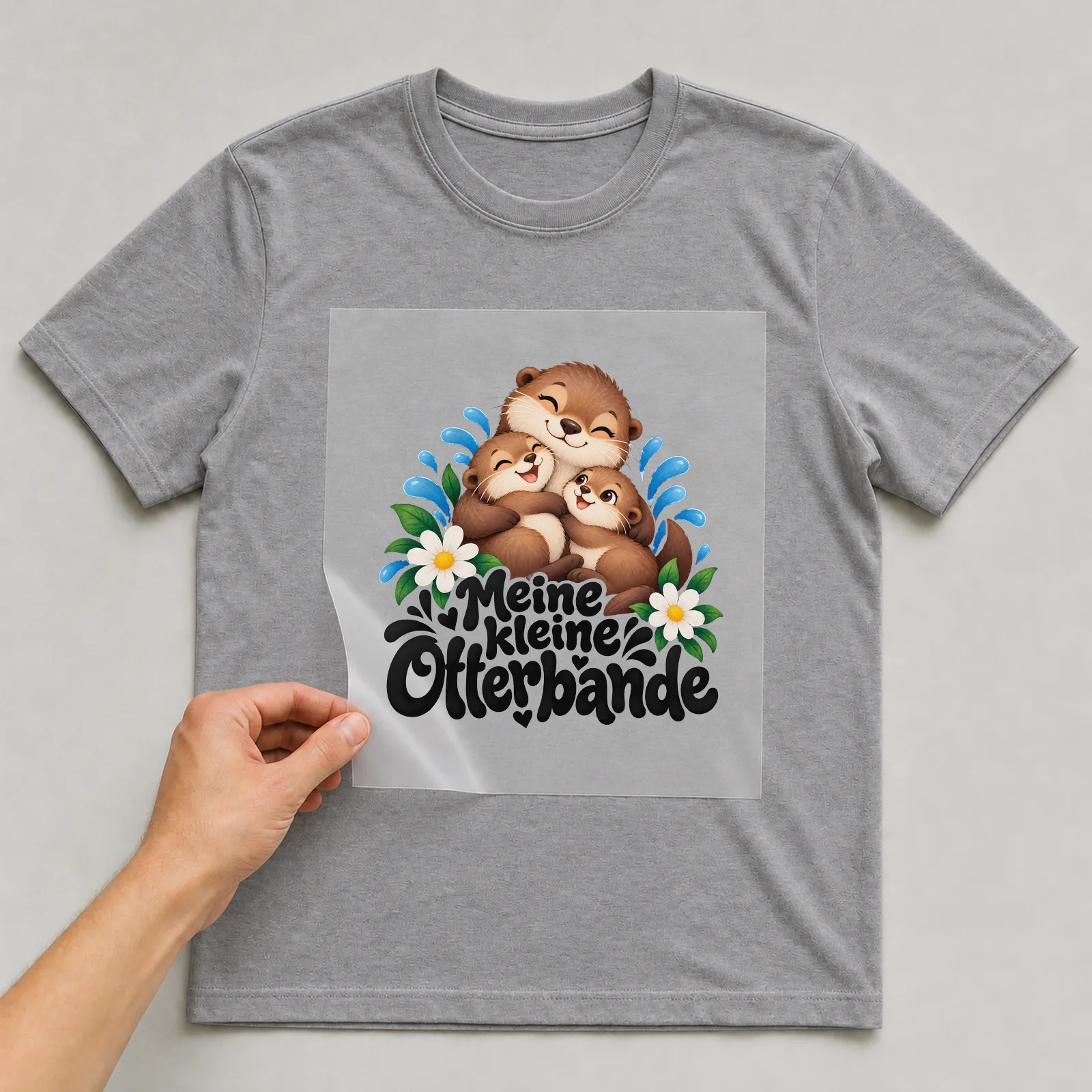 Bügelbild „Meine kleine Otterbande“ (deckendem Aquarell) auf grauem T-Shirt, Folie wird aufgelegt