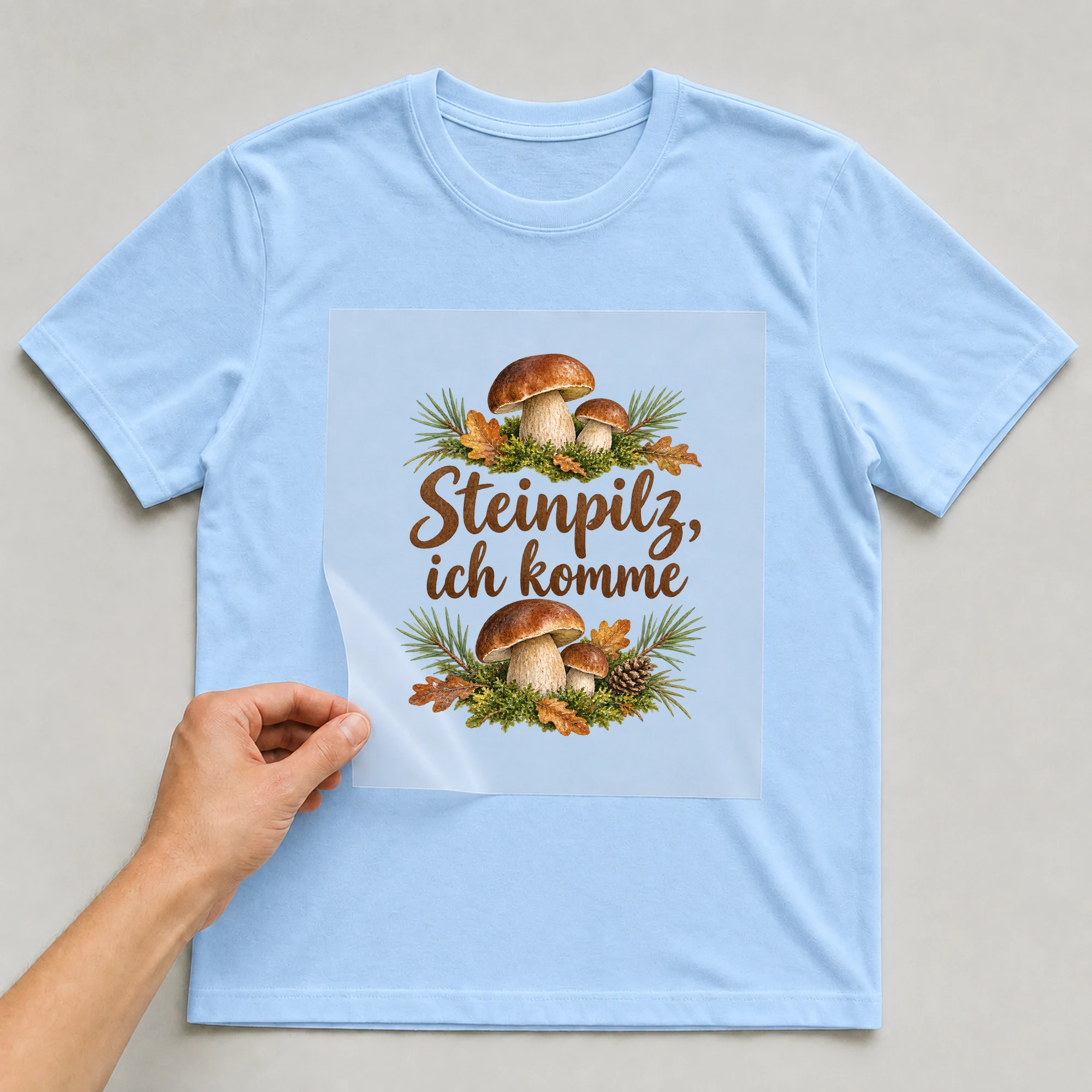 Bügelbild „Steinpilz, ich komme“ auf babyblauem T-Shirt, Folie wird aufgelegt