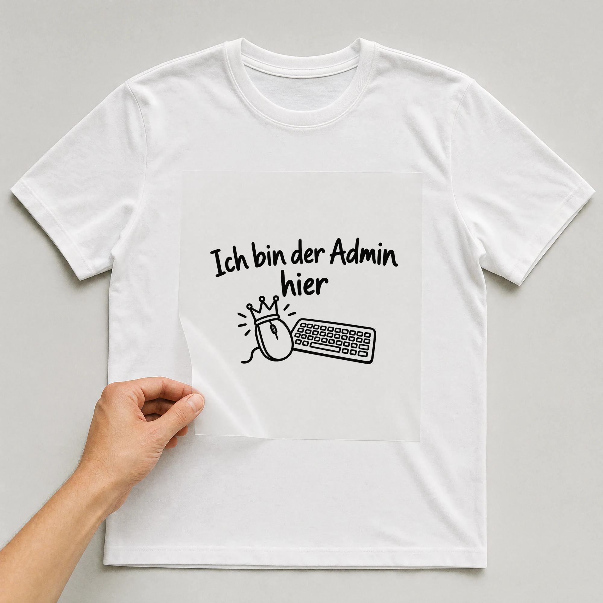 Bügelbild „Ich bin der Admin hier“ auf weißem T-Shirt, Folie wird aufgelegt