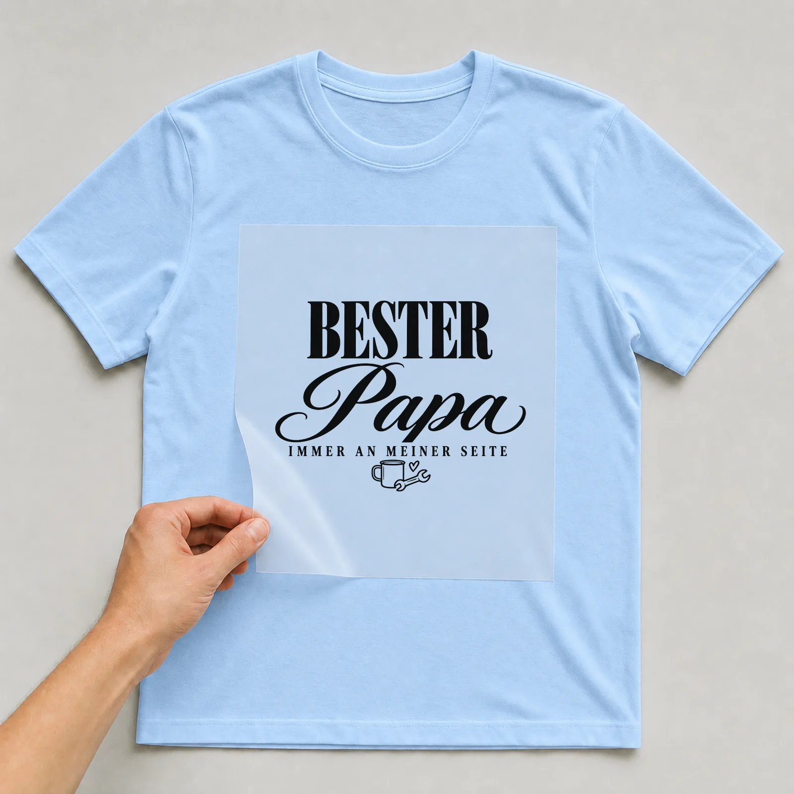 Bügelbild „Bester Papa immer an meiner Seite“ (Club-Schriftzug) auf hellblauem T-Shirt, Folie wird aufgelegt