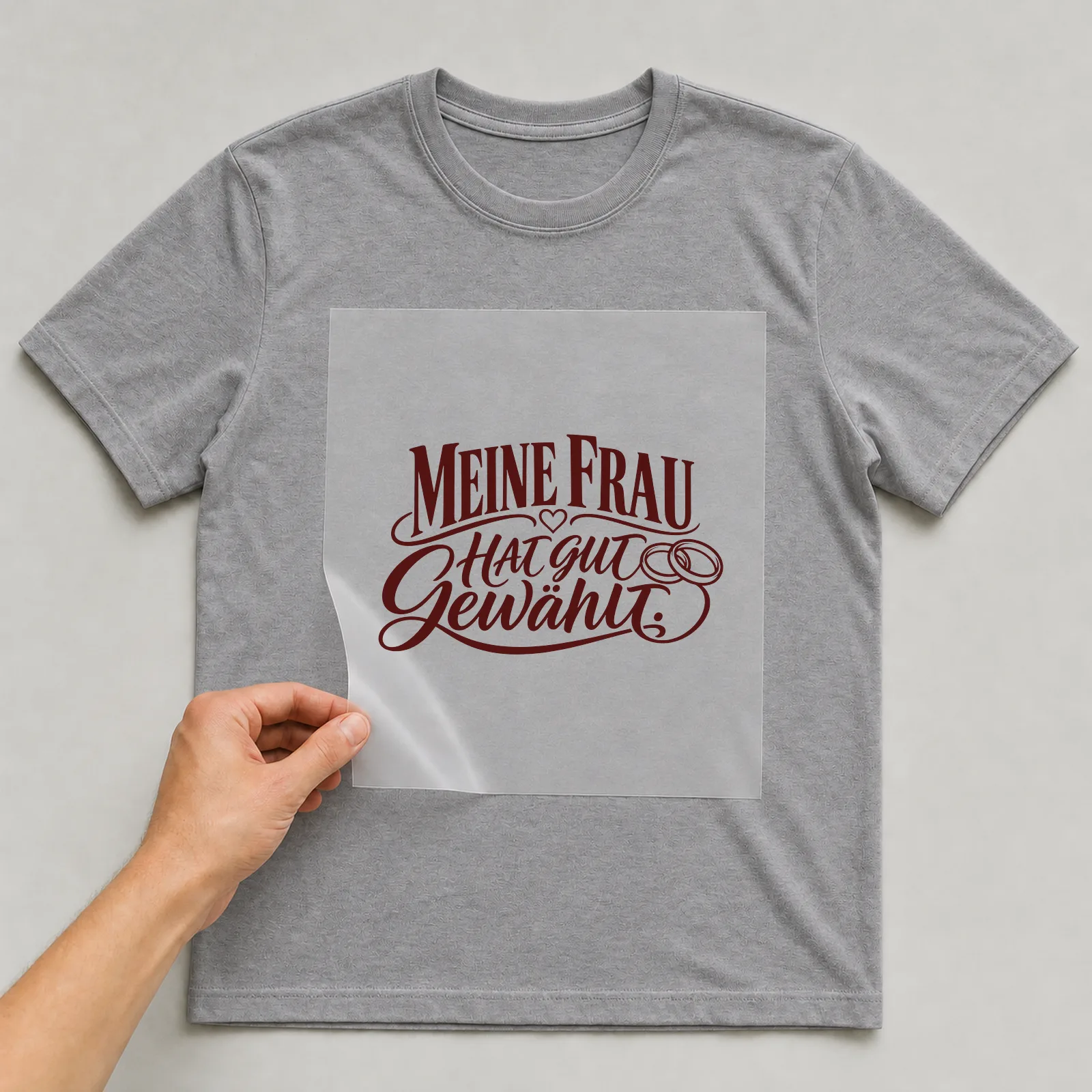 Bügelbild „Meine Frau hat gut gewählt“ auf grauem T-Shirt, Folie wird aufgelegt