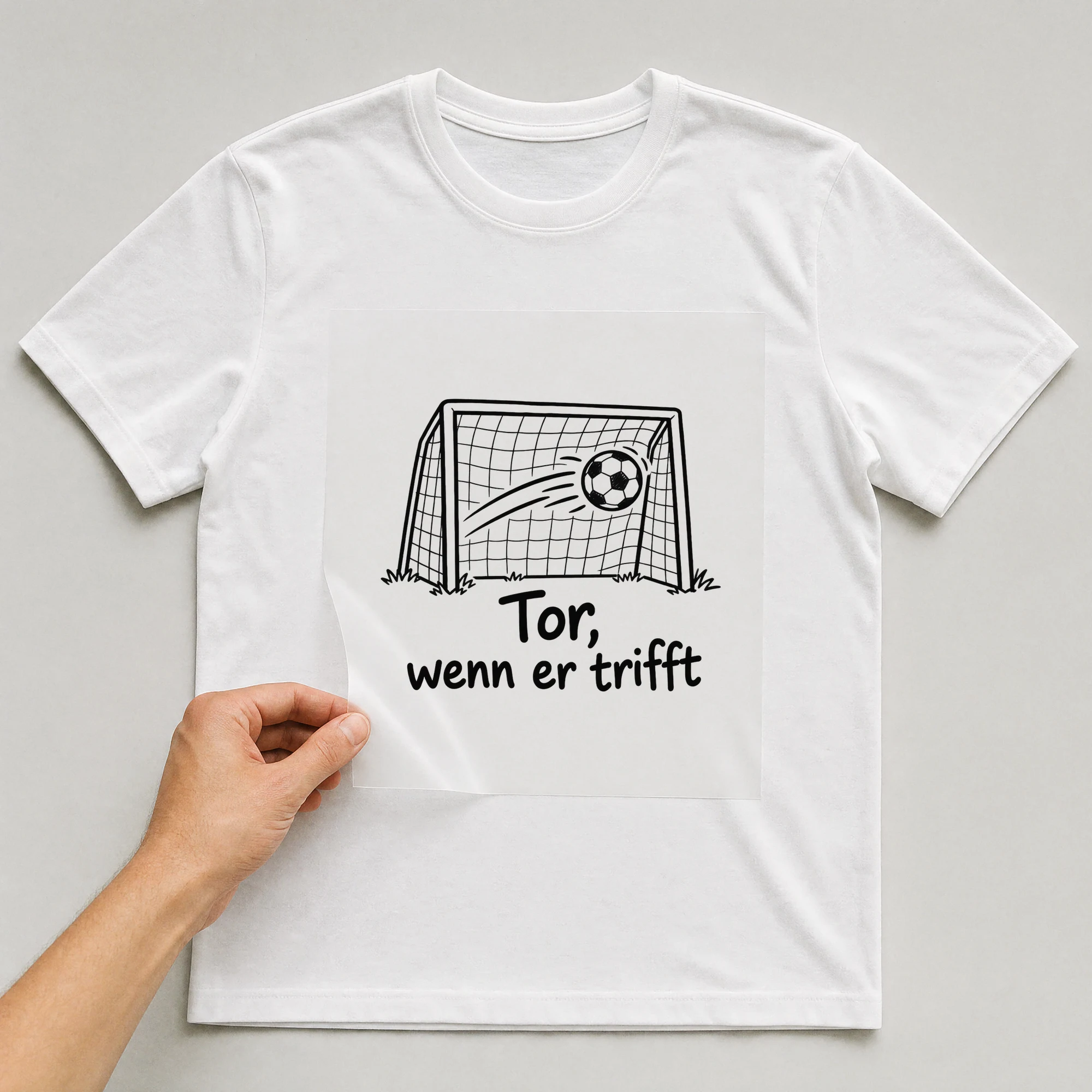 Bügelbild „Tor, wenn er trifft“ auf weißem T-Shirt, Folie wird aufgelegt