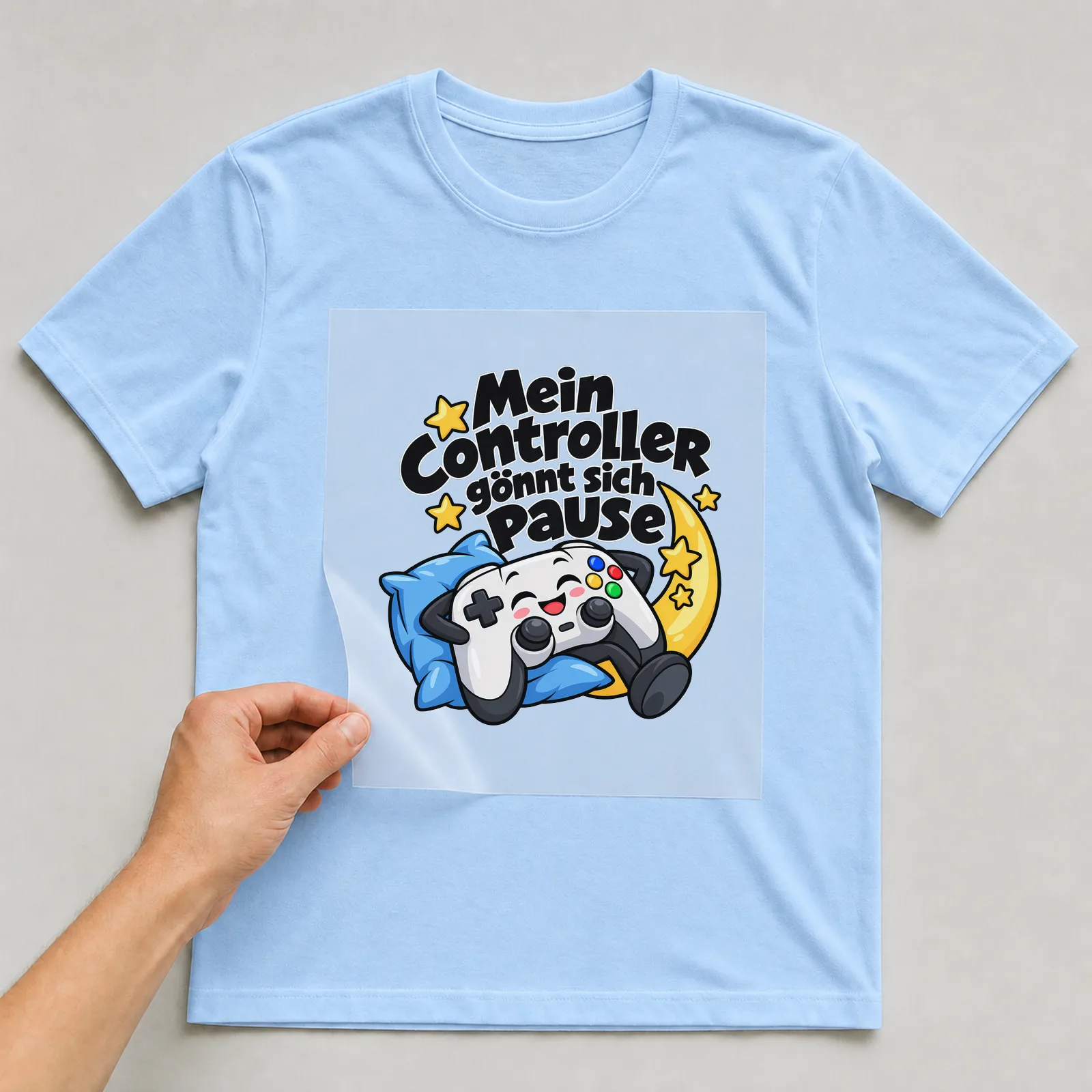 Bügelbild „Mein Controller gönnt sich Pause“ auf hellblauem T-Shirt, Folie wird aufgelegt
