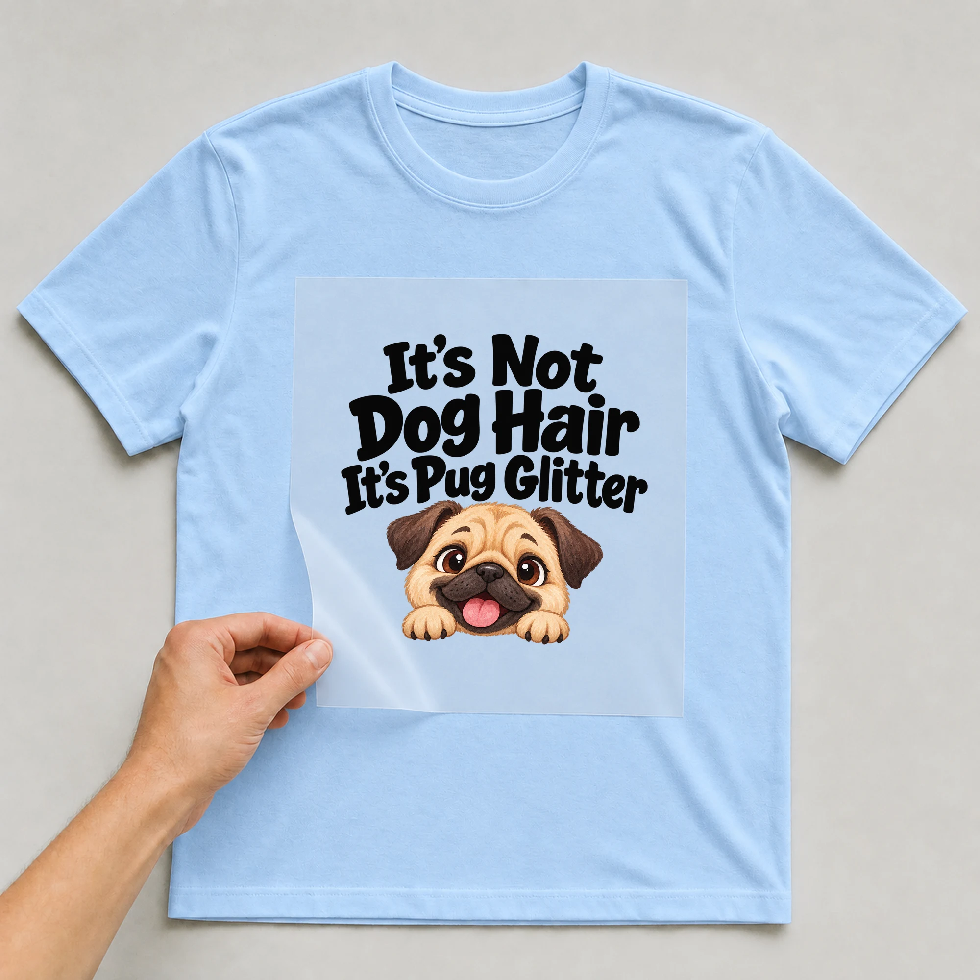 Bügelbild „It's Not Dog Hair It's Pug Glitter“ auf babyblauem T-Shirt, Folie wird aufgelegt