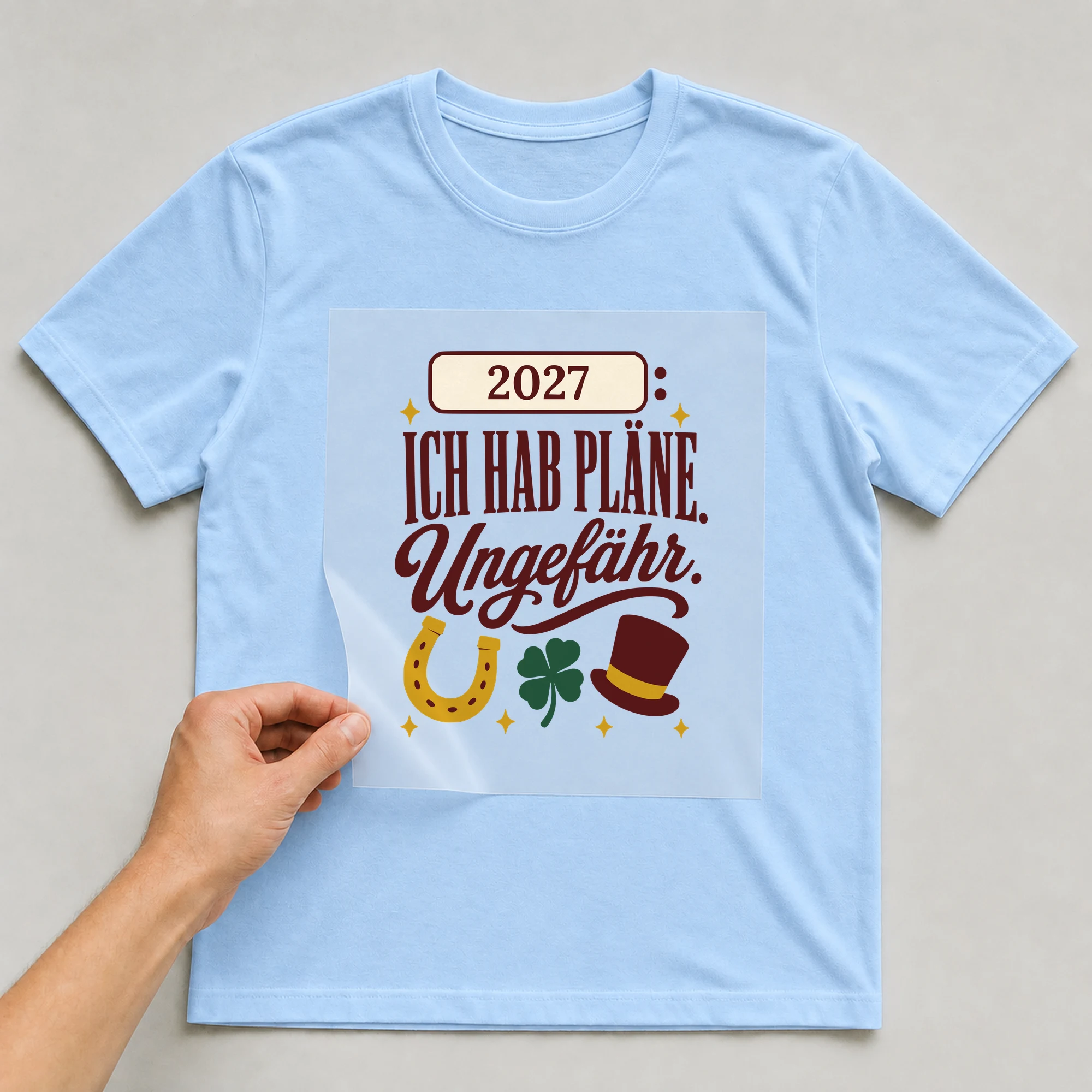 Bügelbild Ich hab Pläne. Ungefähr. mit Jahr auf hellblauem T-Shirt, Folie wird aufgelegt