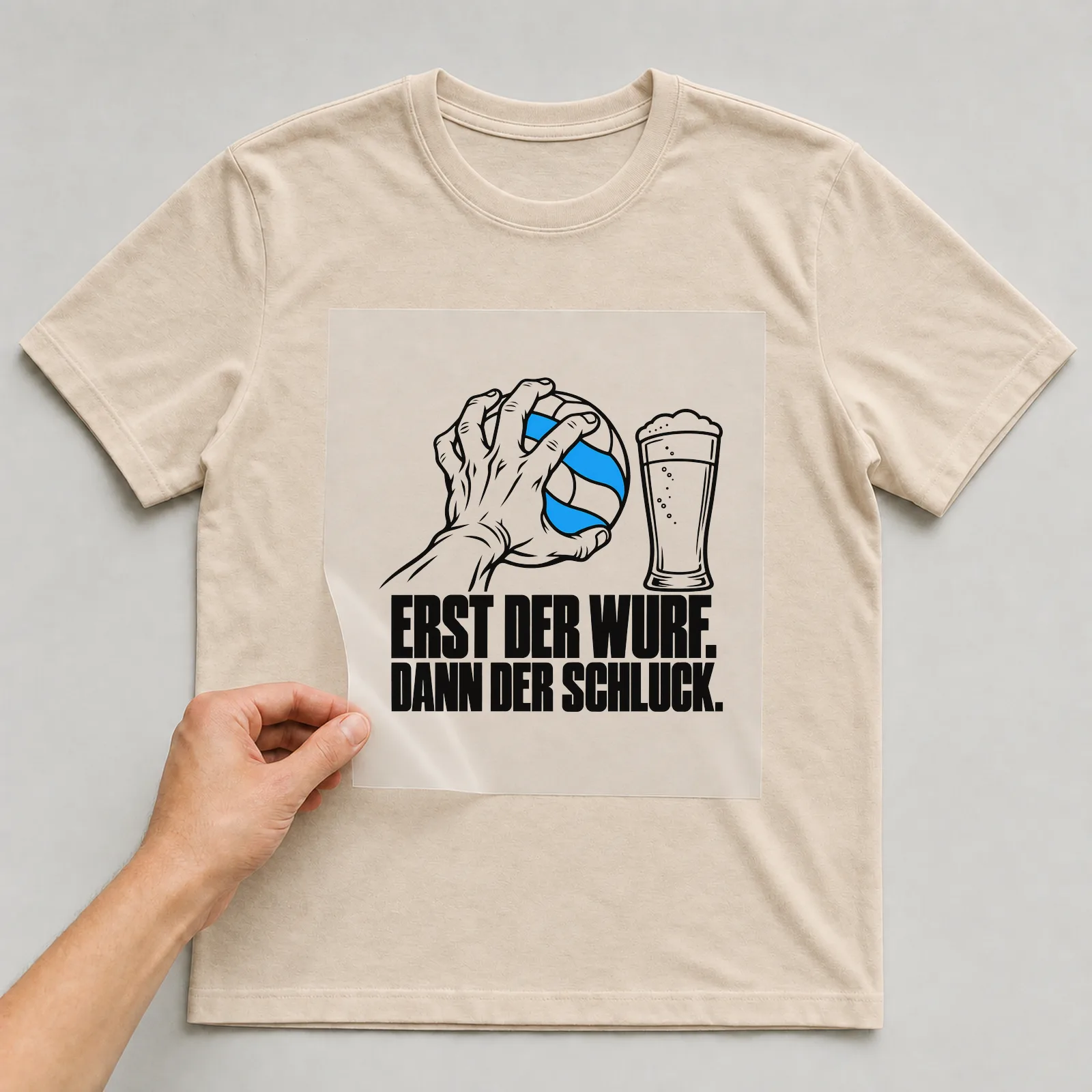 Bügelbild „Erst der Wurf. Dann der Schluck.“ auf beigem T-Shirt, Folie wird aufgelegt