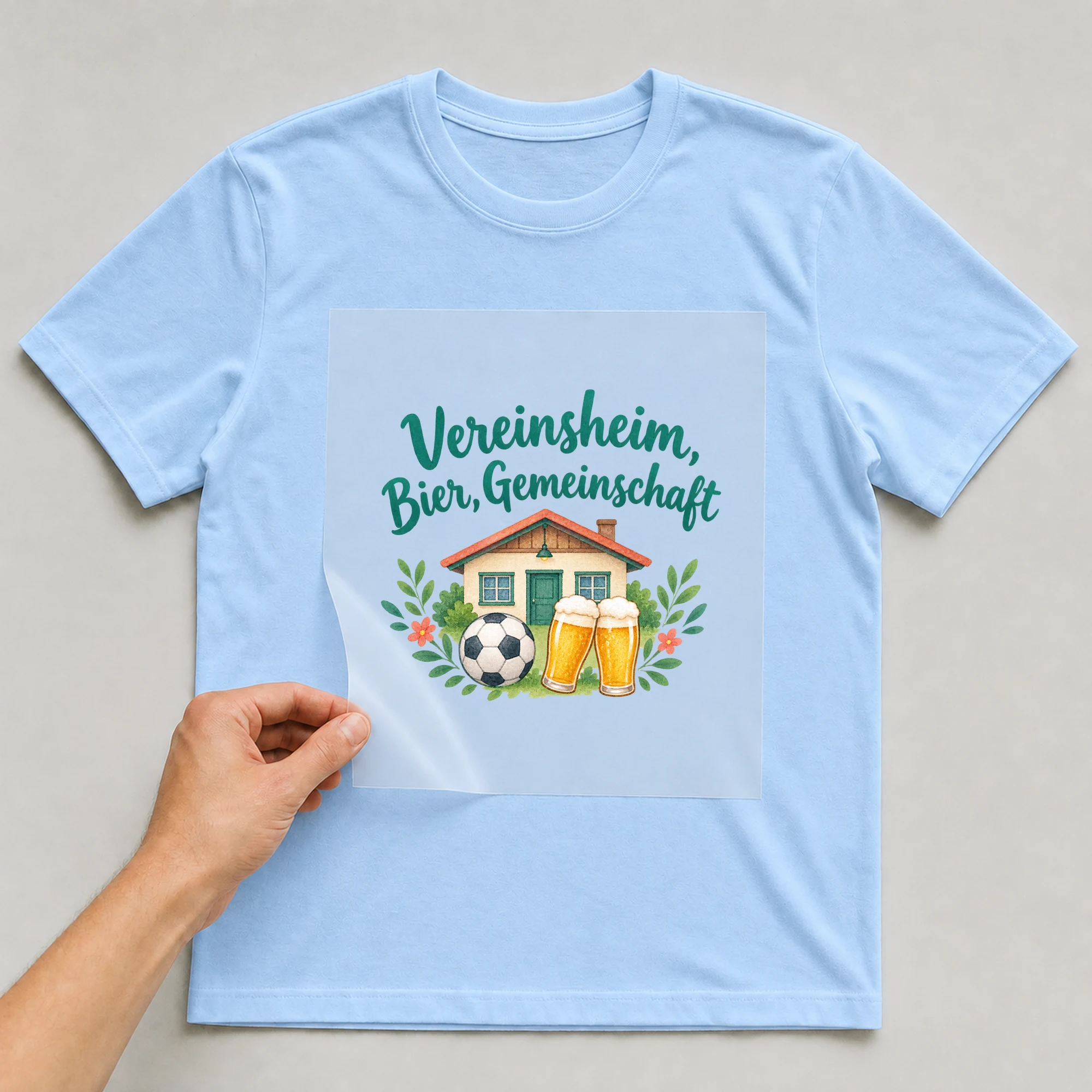 Bügelbild „Vereinsheim, Bier, Gemeinschaft“ auf babyblauem T-Shirt, Folie wird aufgelegt