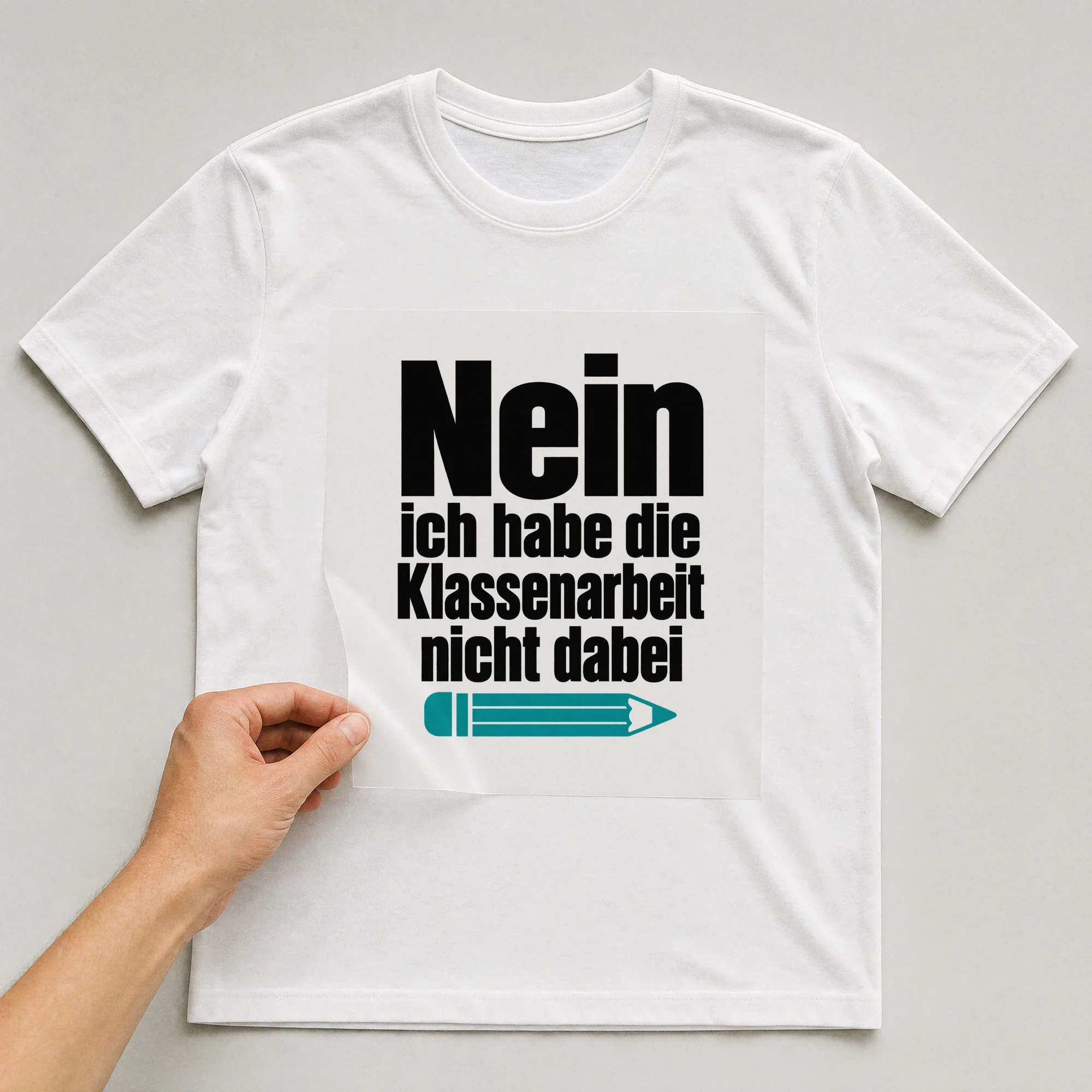 Bügelbild „Nein ich habe die Klassenarbeit nicht dabei“ auf weißem T-Shirt, Folie wird aufgelegt