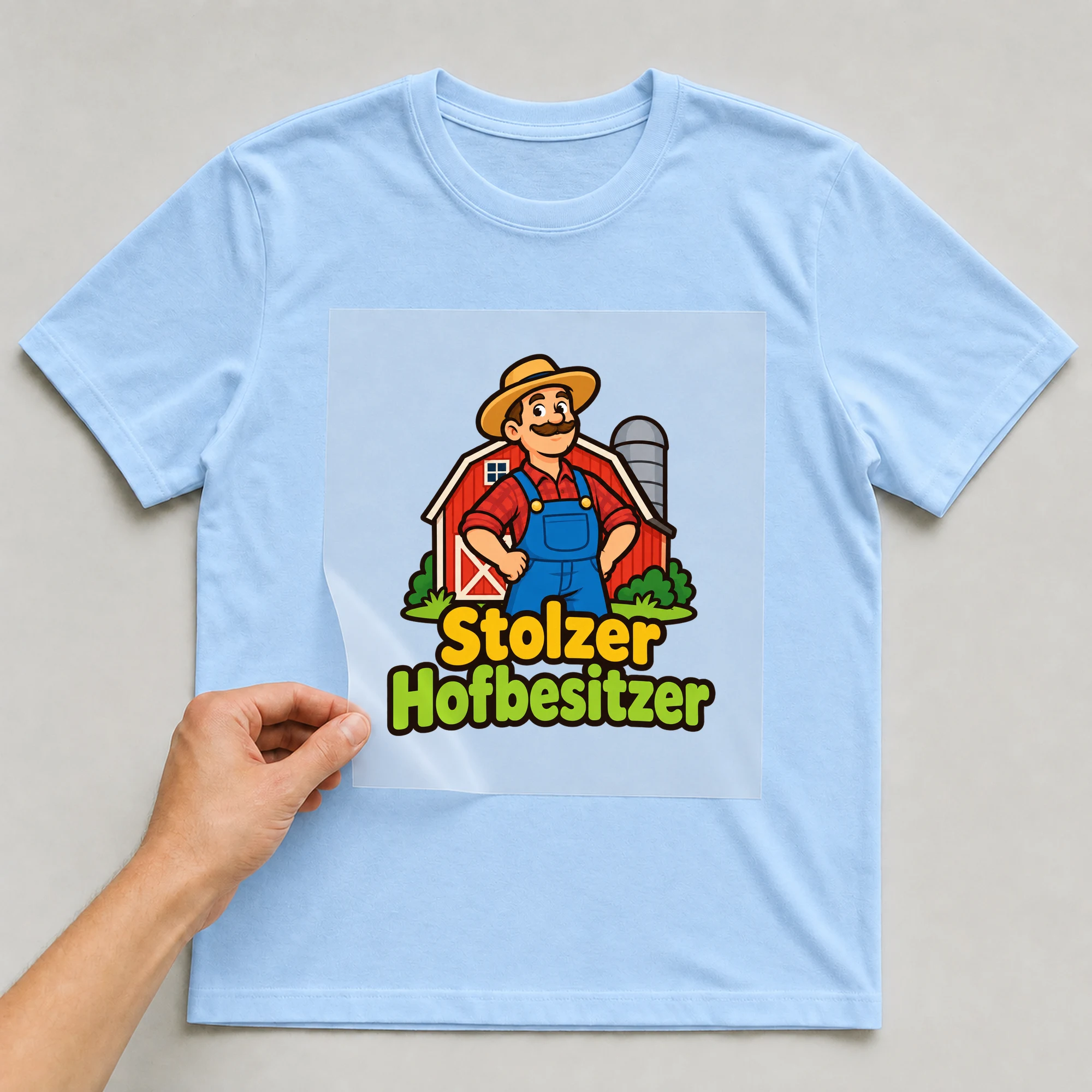 Bügelbild „Stolzer Hofbesitzer“ auf babyblauem T-Shirt, Folie wird aufgelegt