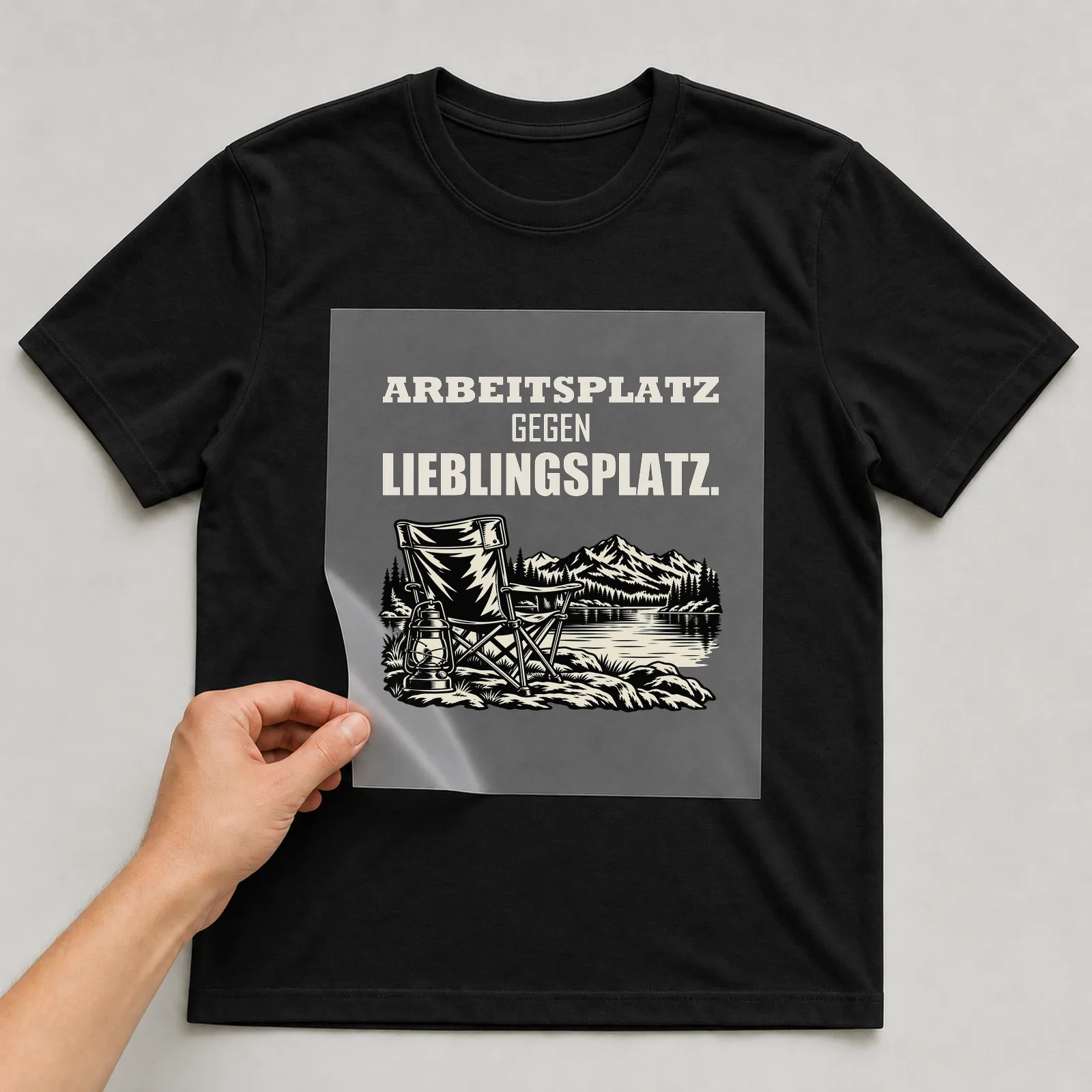 Bügelbild „Arbeitsplatz gegen Lieblingsplatz“ auf schwarzem T-Shirt, Folie wird aufgelegt