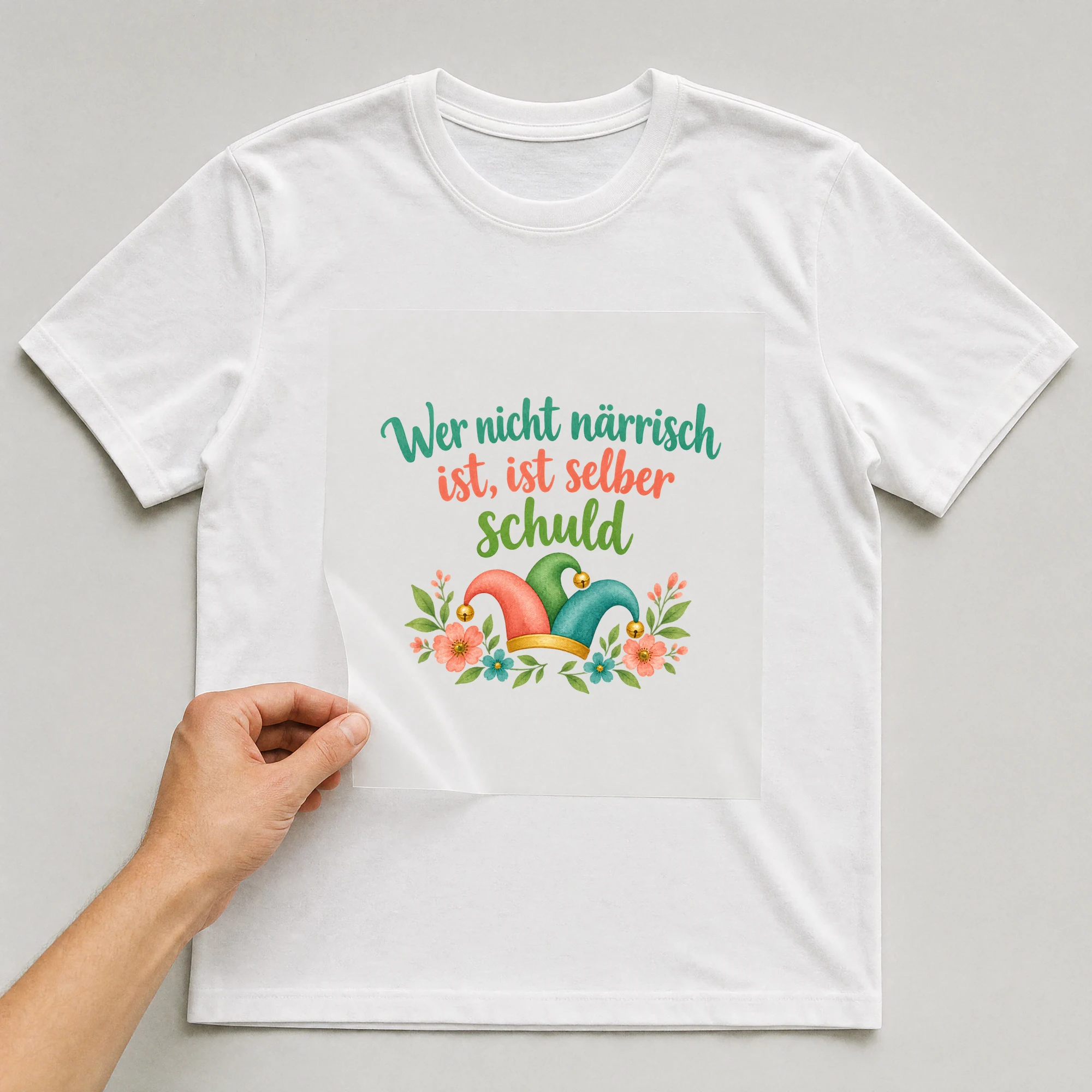 Bügelbild „Wer nicht närrisch ist, ist selber schuld“ auf weißem T-Shirt, Folie wird aufgelegt