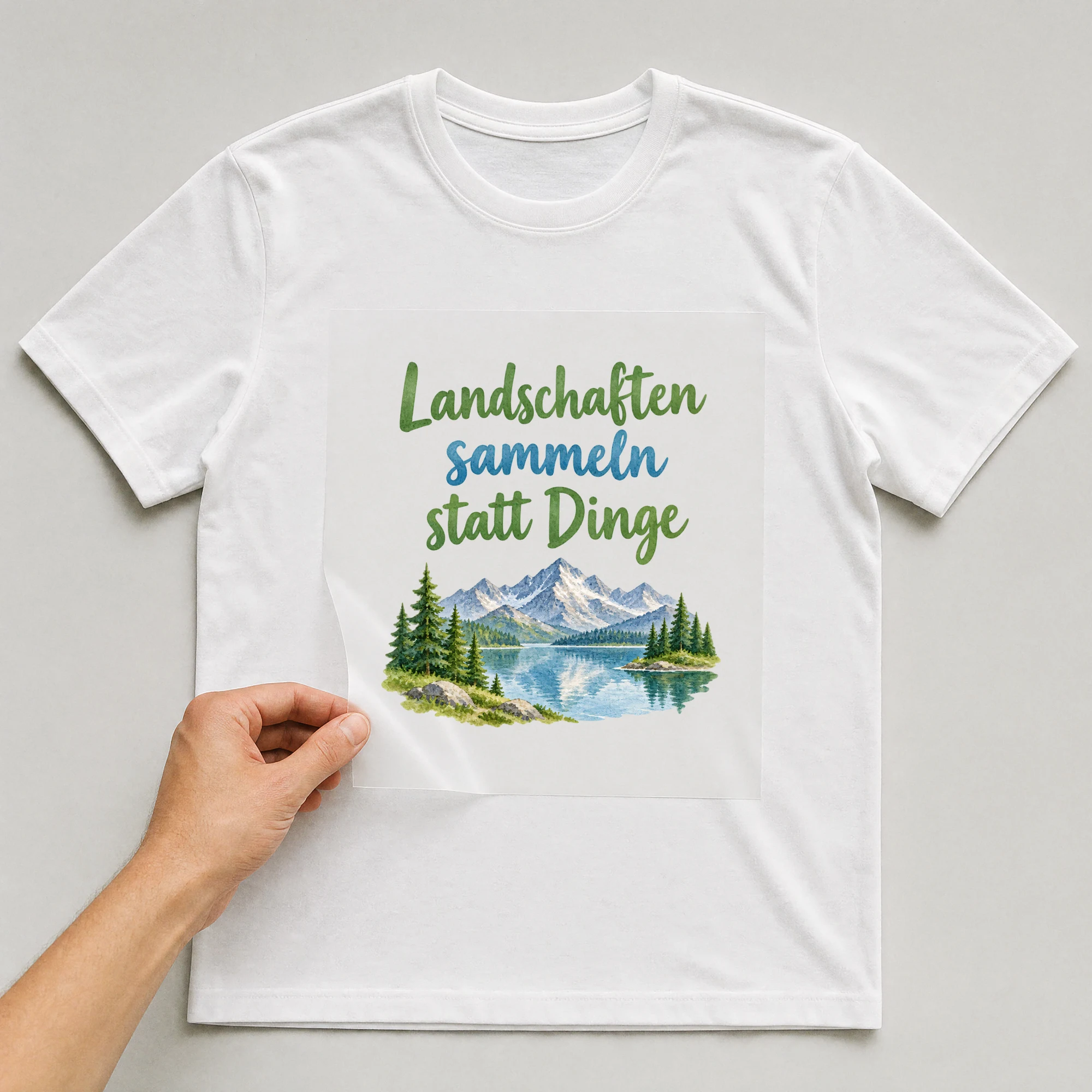 Bügelbild „Landschaften sammeln statt Dinge“ auf weißem T-Shirt, Folie wird aufgelegt