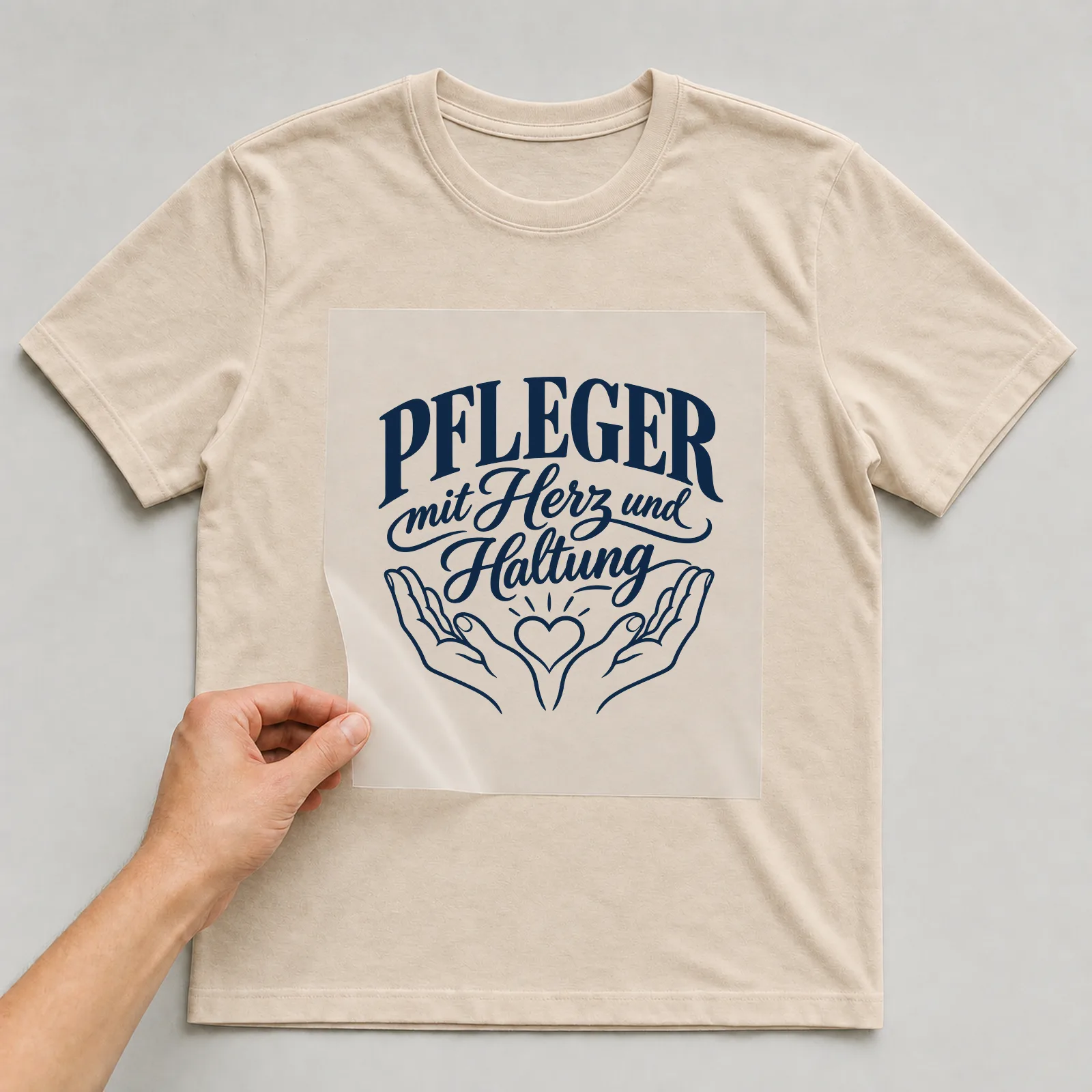 Bügelbild „Pfleger mit Herz und Haltung“ auf beigem T-Shirt, Folie wird aufgelegt