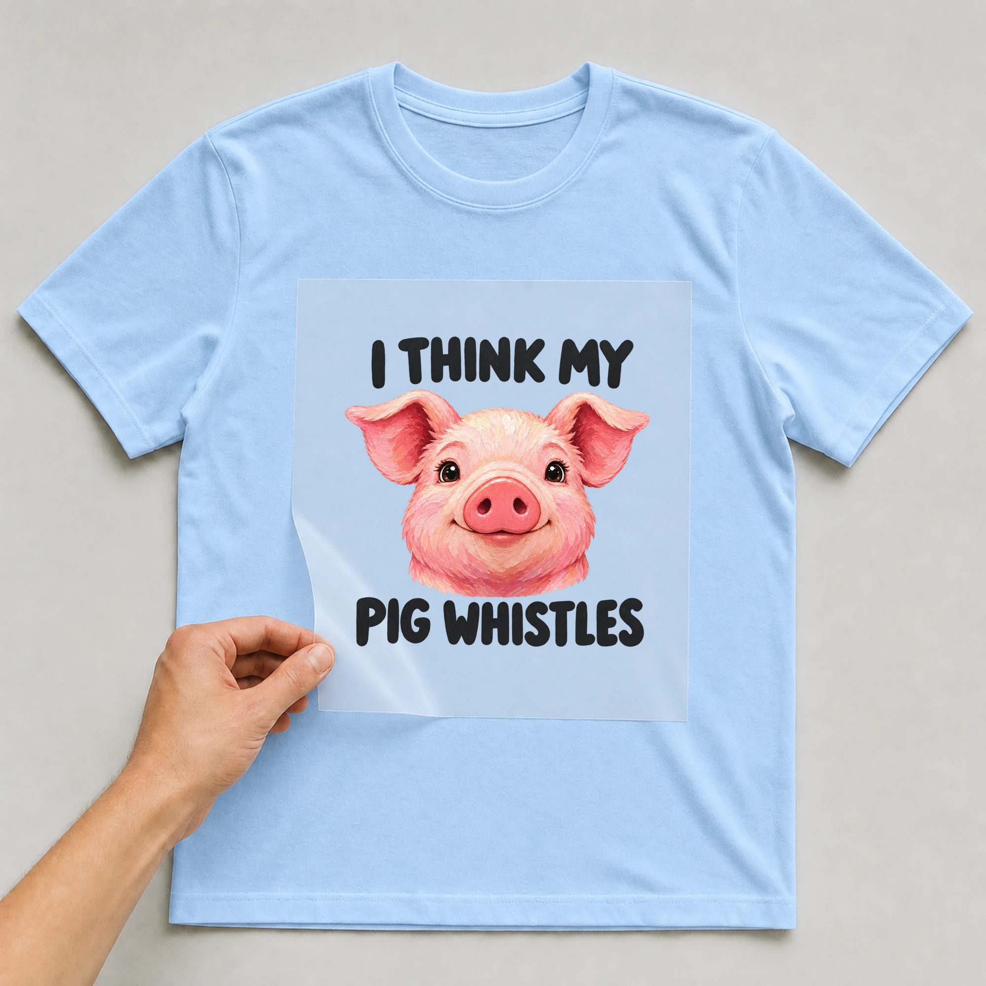 Bügelbild „I Think My Pig Whistles“ auf babyblauem T-Shirt, Folie wird aufgelegt