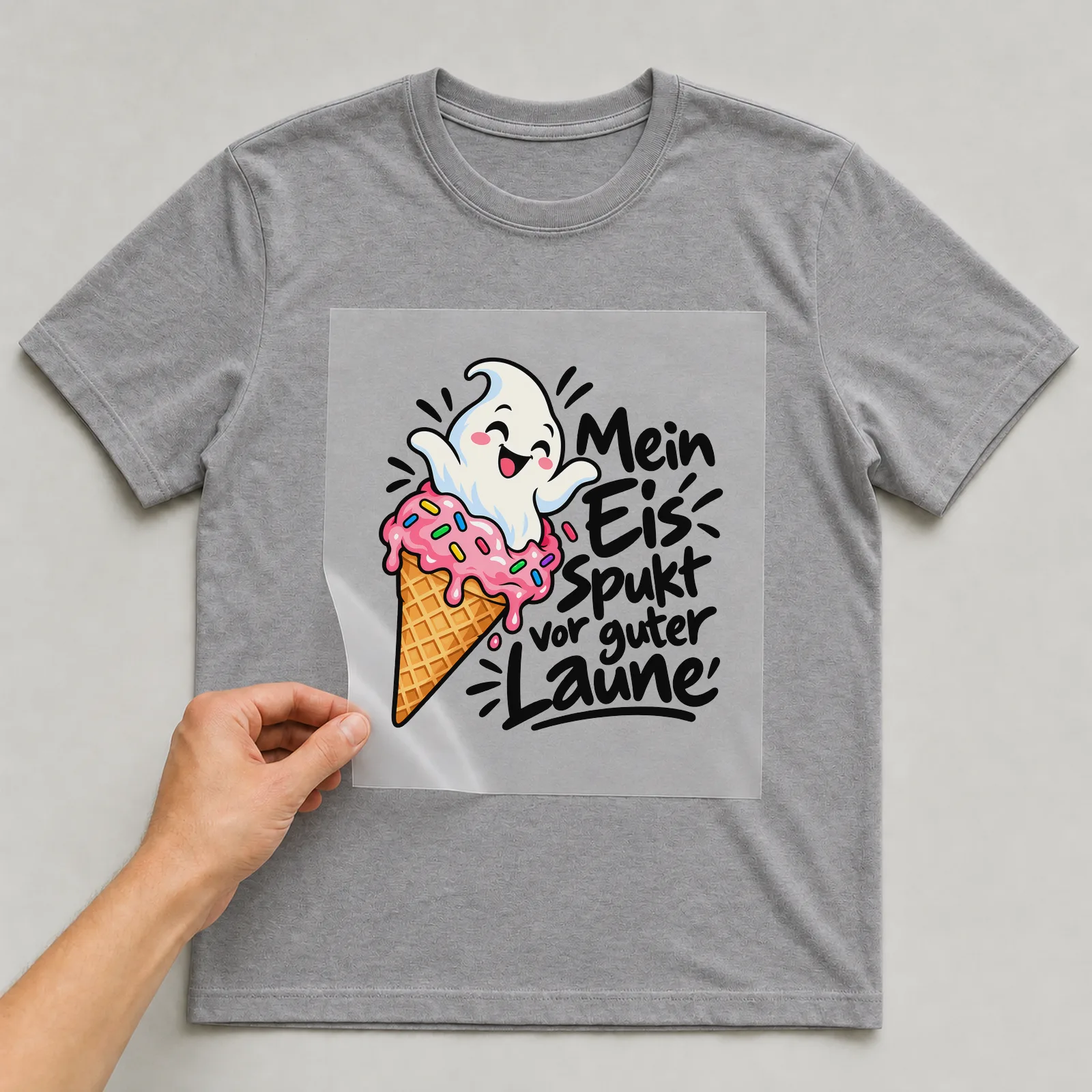 Bügelbild „Mein Eis spukt vor guter Laune“ auf grauem T-Shirt, Folie wird aufgelegt