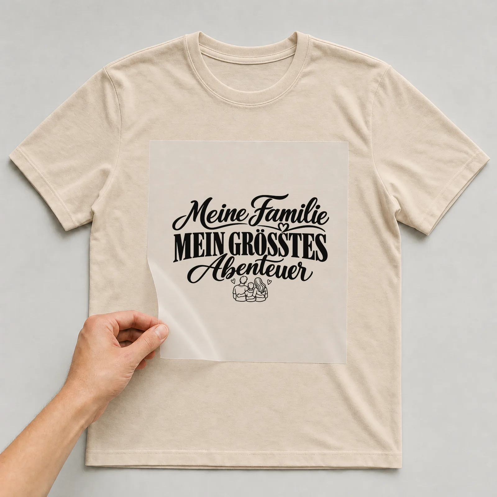 Bügelbild „Meine Familie mein größtes Abenteuer“ auf beigem T-Shirt, Folie wird aufgelegt