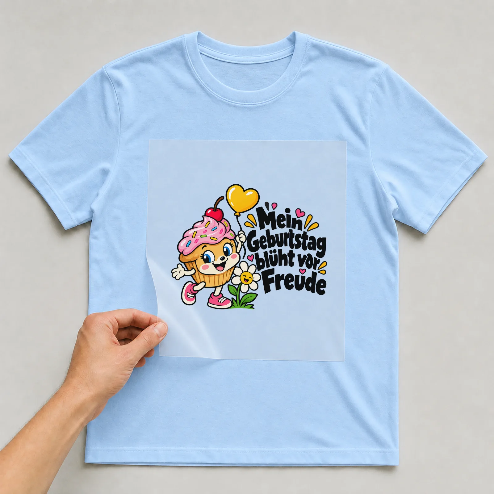 Bügelbild „Mein Geburtstag blüht vor Freude“ auf hellblauem T-Shirt, Folie wird aufgelegt