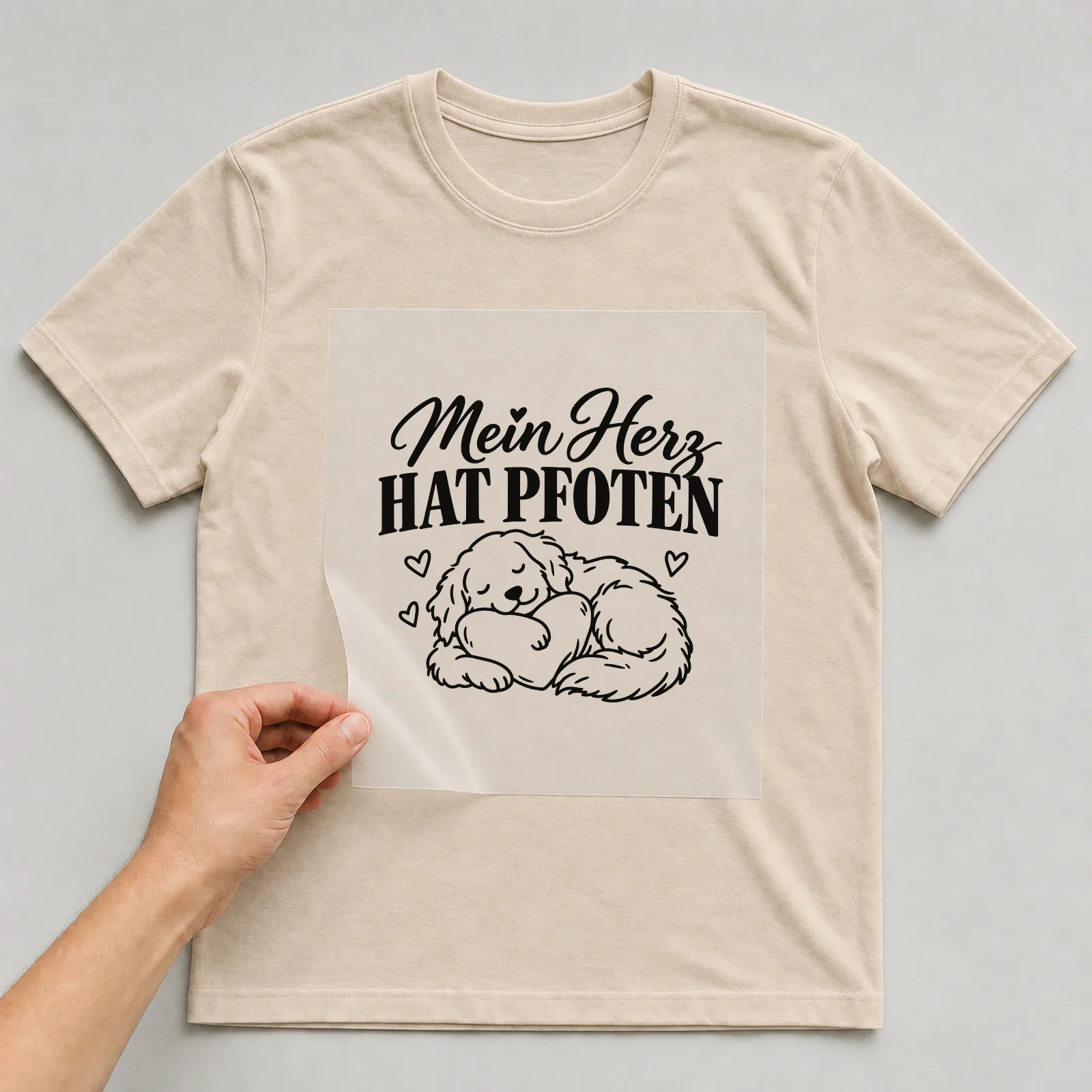 Bügelbild „Mein Herz hat Pfoten“ auf beigem T-Shirt, Folie wird aufgelegt