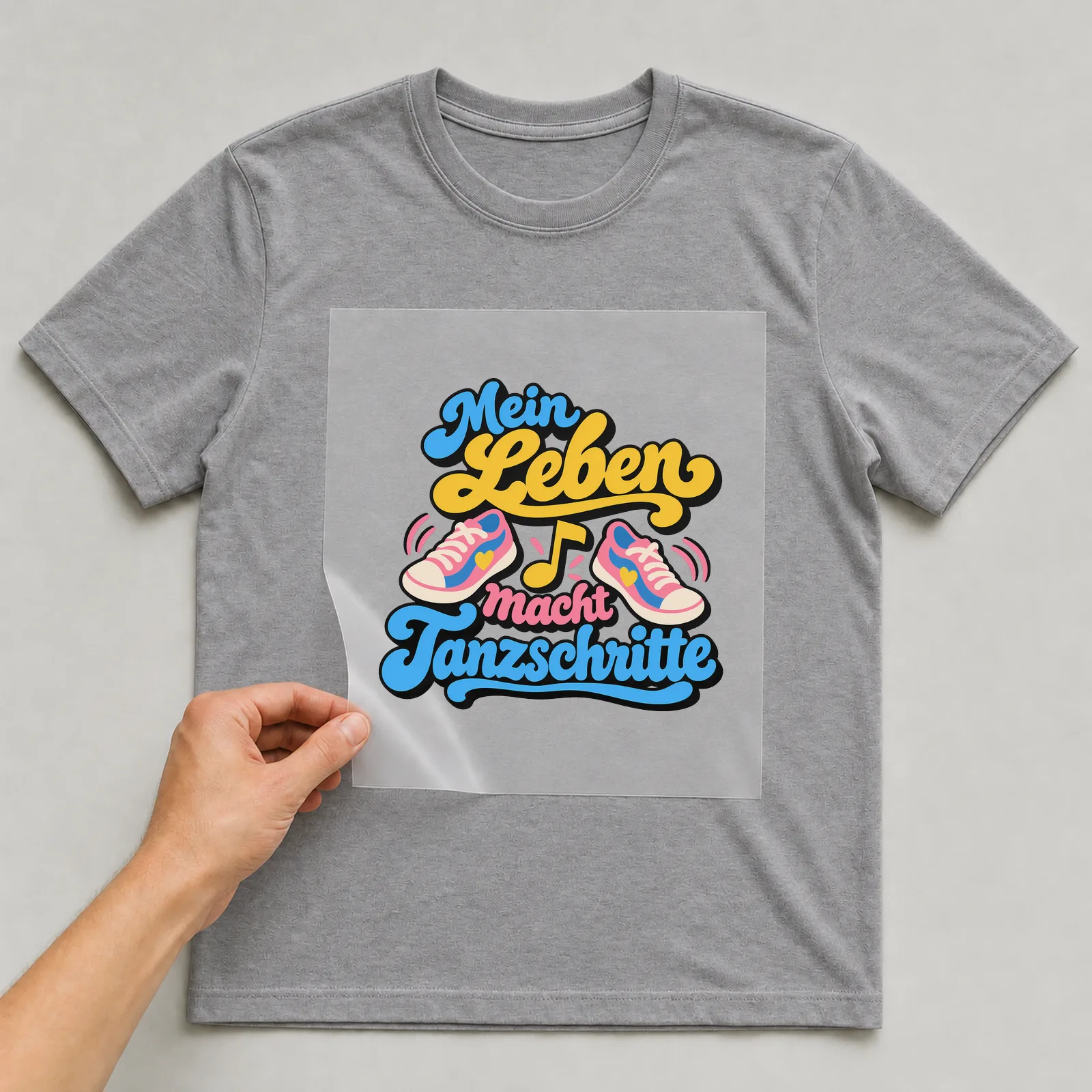 Bügelbild „Mein Leben macht Tanzschritte“ auf grauem T-Shirt, Folie wird aufgelegt
