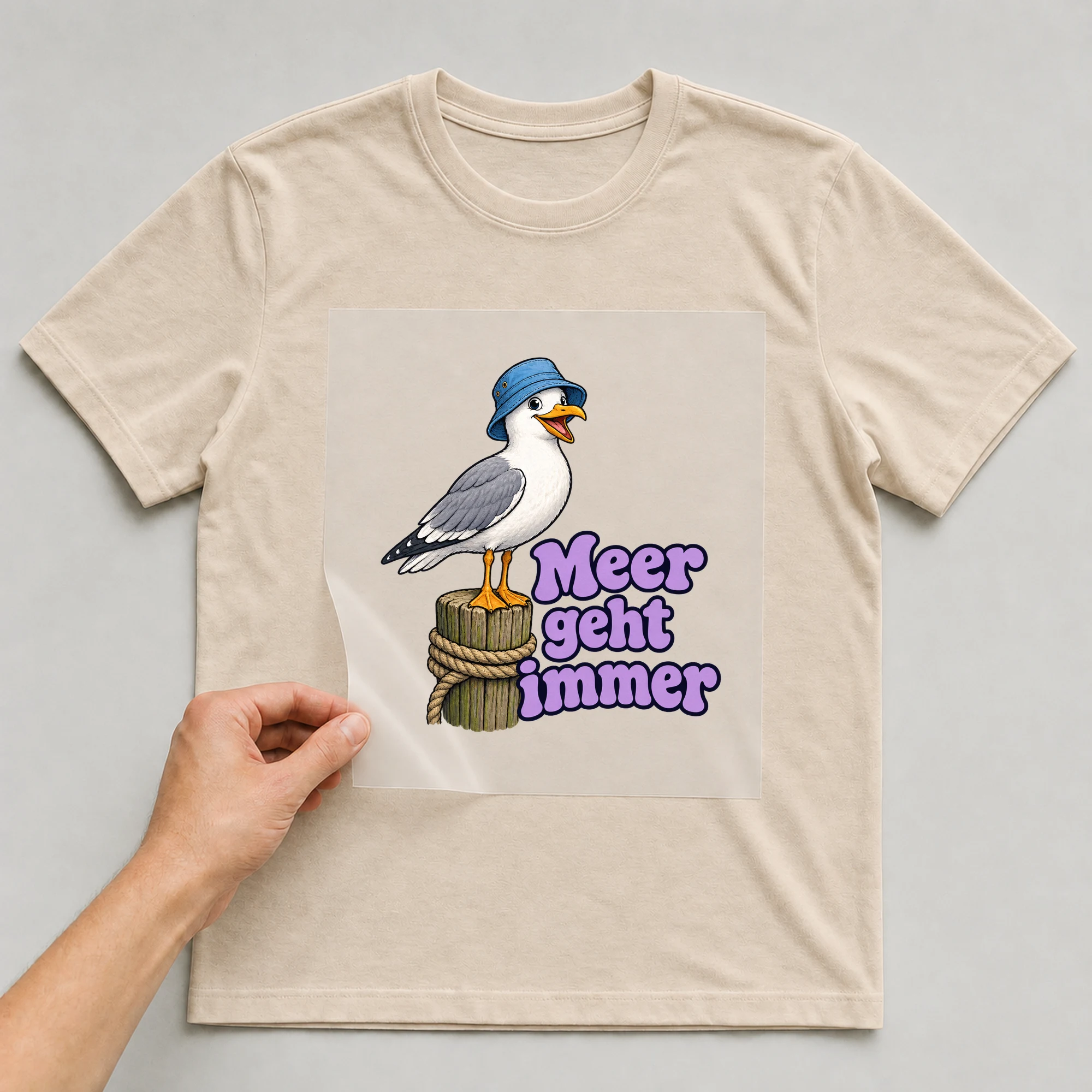 Bügelbild „Meer geht immer“ auf beigem T-Shirt, Folie wird aufgelegt