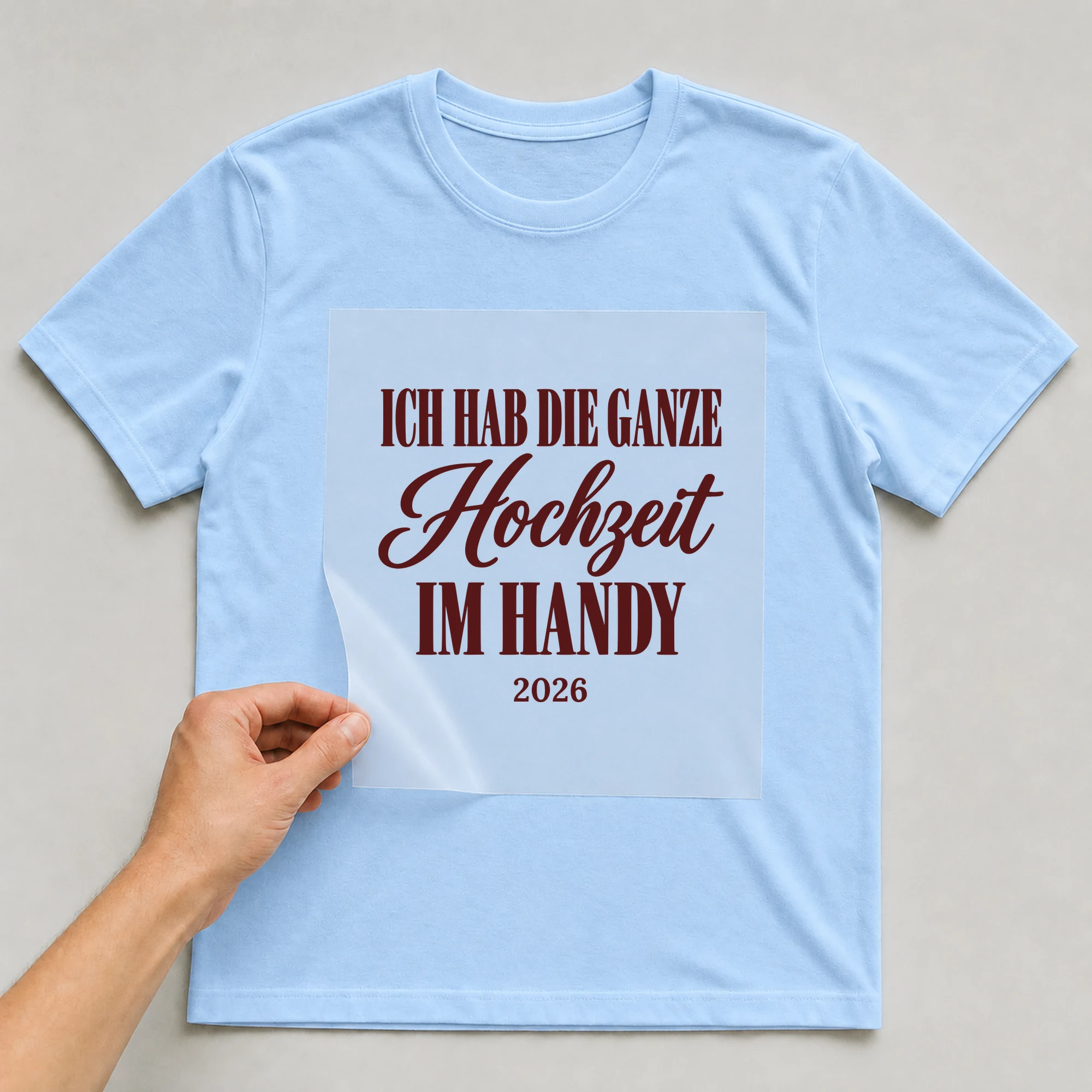 Bügelbild Ich hab die ganze Hochzeit im Handy mit Jahr auf hellblauem T-Shirt, Folie wird aufgelegt