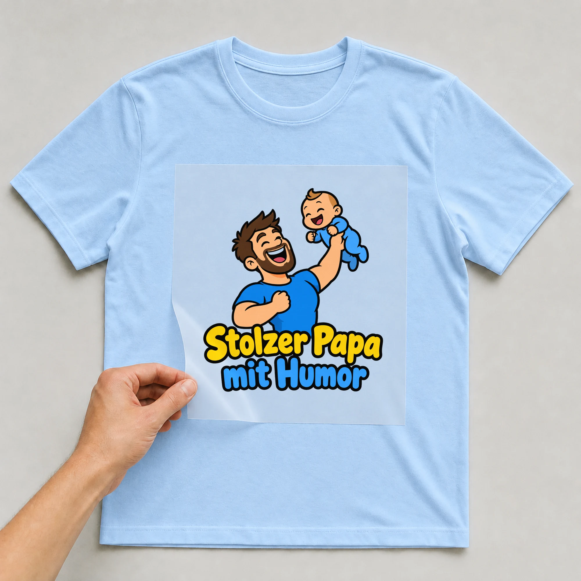 Bügelbild „Stolzer Papa mit Humor“ auf babyblauem T-Shirt, Folie wird aufgelegt