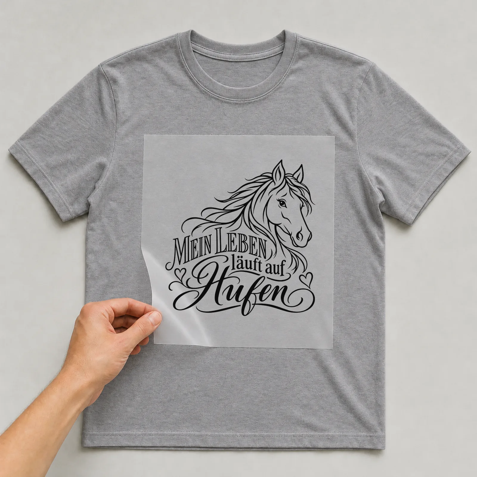 Bügelbild „Mein Leben läuft auf Hufen“ auf grauem T-Shirt, Folie wird aufgelegt
