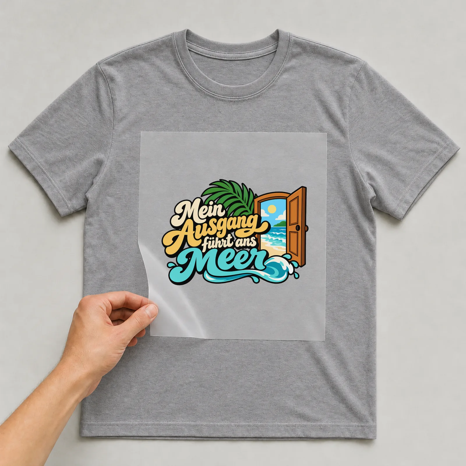 Bügelbild „Mein Ausgang führt ans Meer“ auf grauem T-Shirt, Folie wird aufgelegt