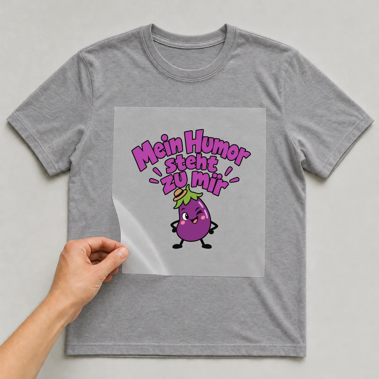 Bügelbild „Mein Humor steht zu mir“ auf grauem T-Shirt, Folie wird aufgelegt