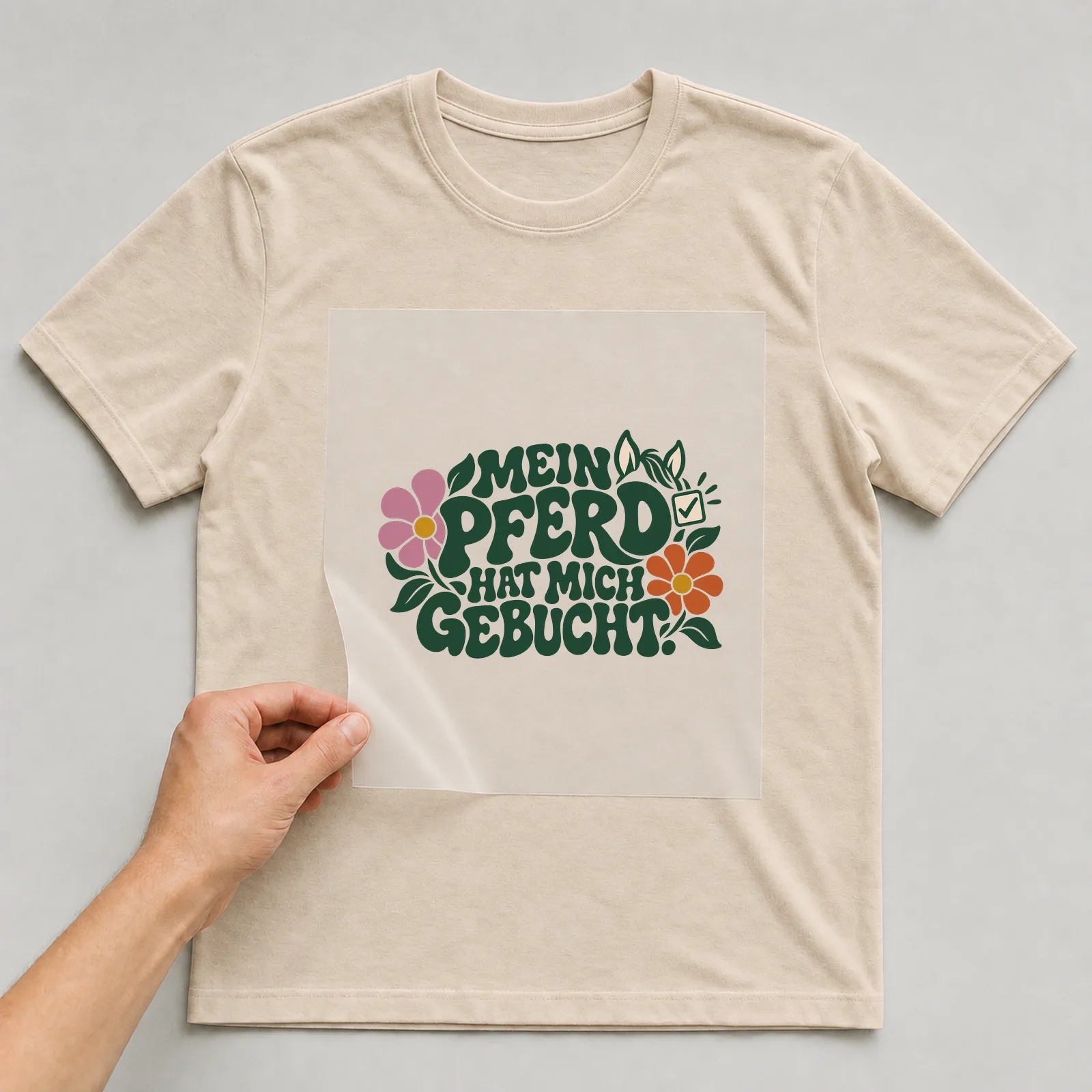 Bügelbild „Mein Pferd hat mich gebucht“ auf beigem T-Shirt, Folie wird aufgelegt