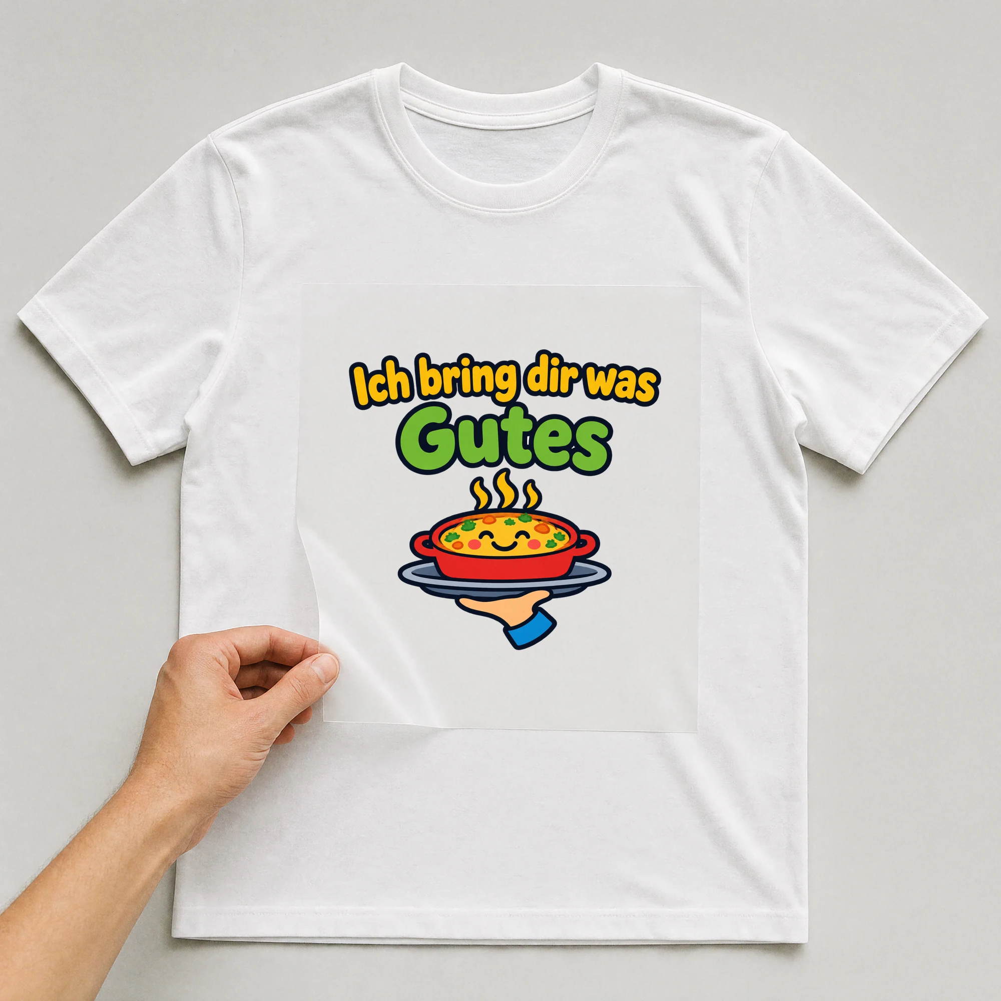 Bügelbild „Ich bring dir was Gutes“ auf weißem T-Shirt, Folie wird aufgelegt