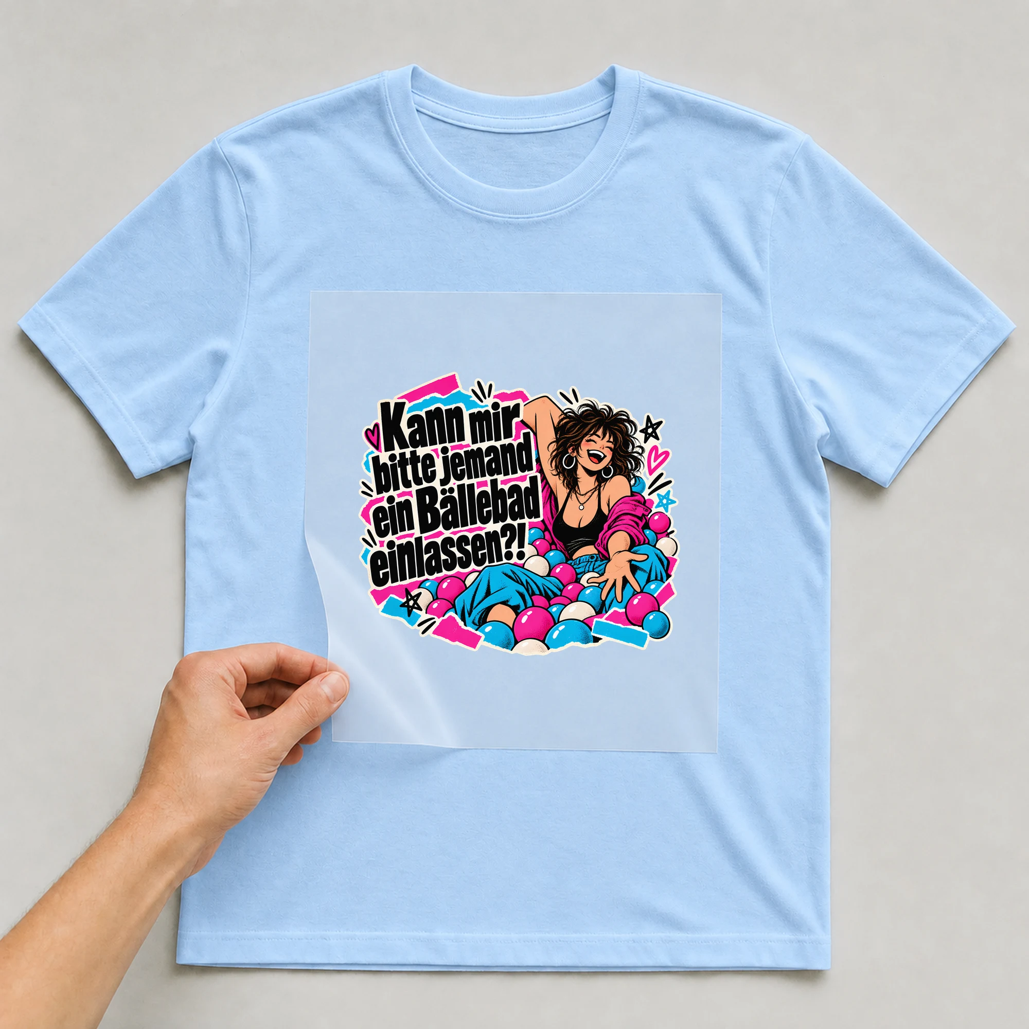 Bügelbild „Kann mir bitte jemand ein Bällebad einlassen?!“ auf babyblauem T-Shirt, Folie wird aufgelegt