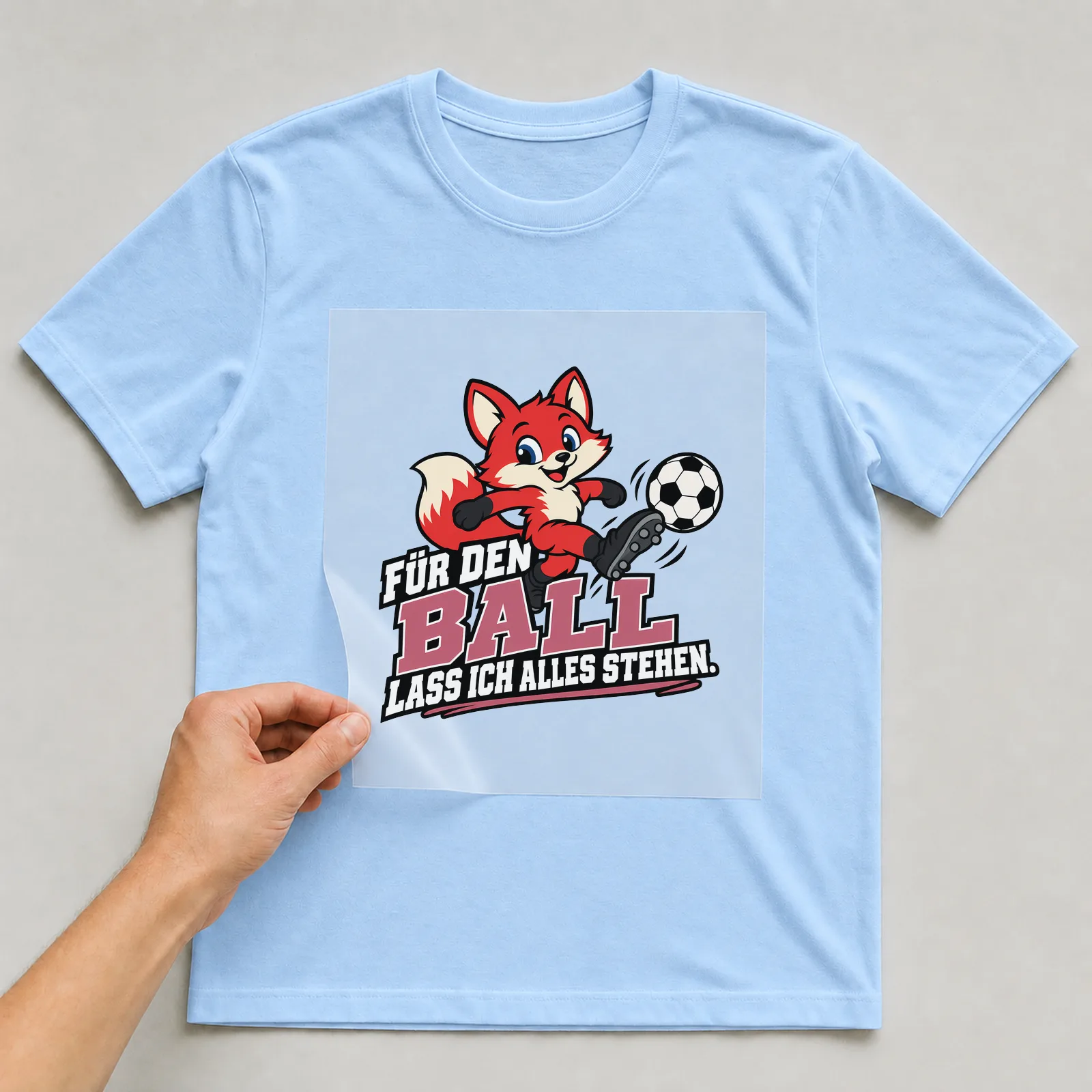 Bügelbild „Für den Ball lass ich alles stehen“ auf hellblauem T-Shirt, Folie wird aufgelegt
