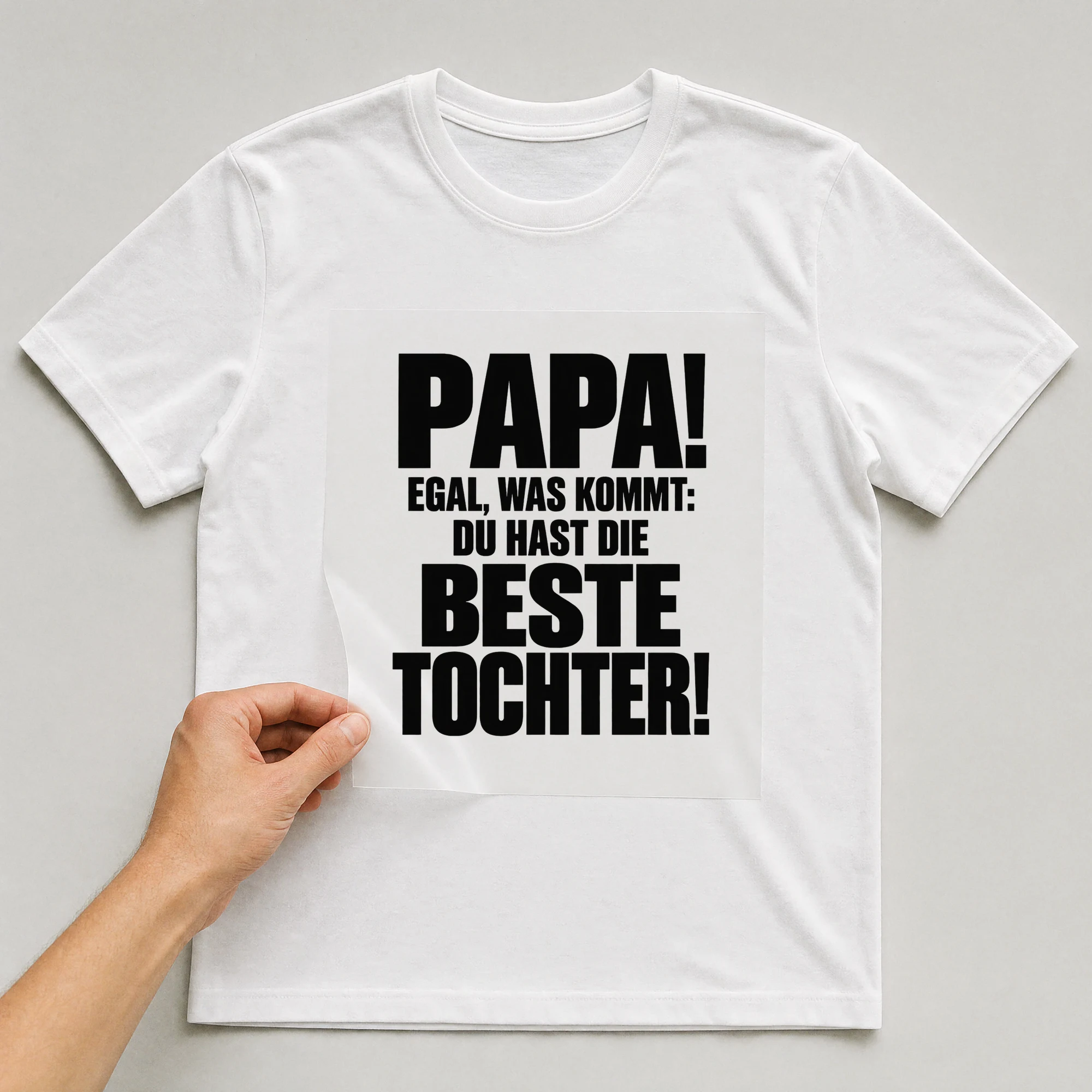 Bügelbild „Papa! Egal, was kommt: Du hast die beste Tochter!“ auf weißem T-Shirt, Folie wird aufgelegt