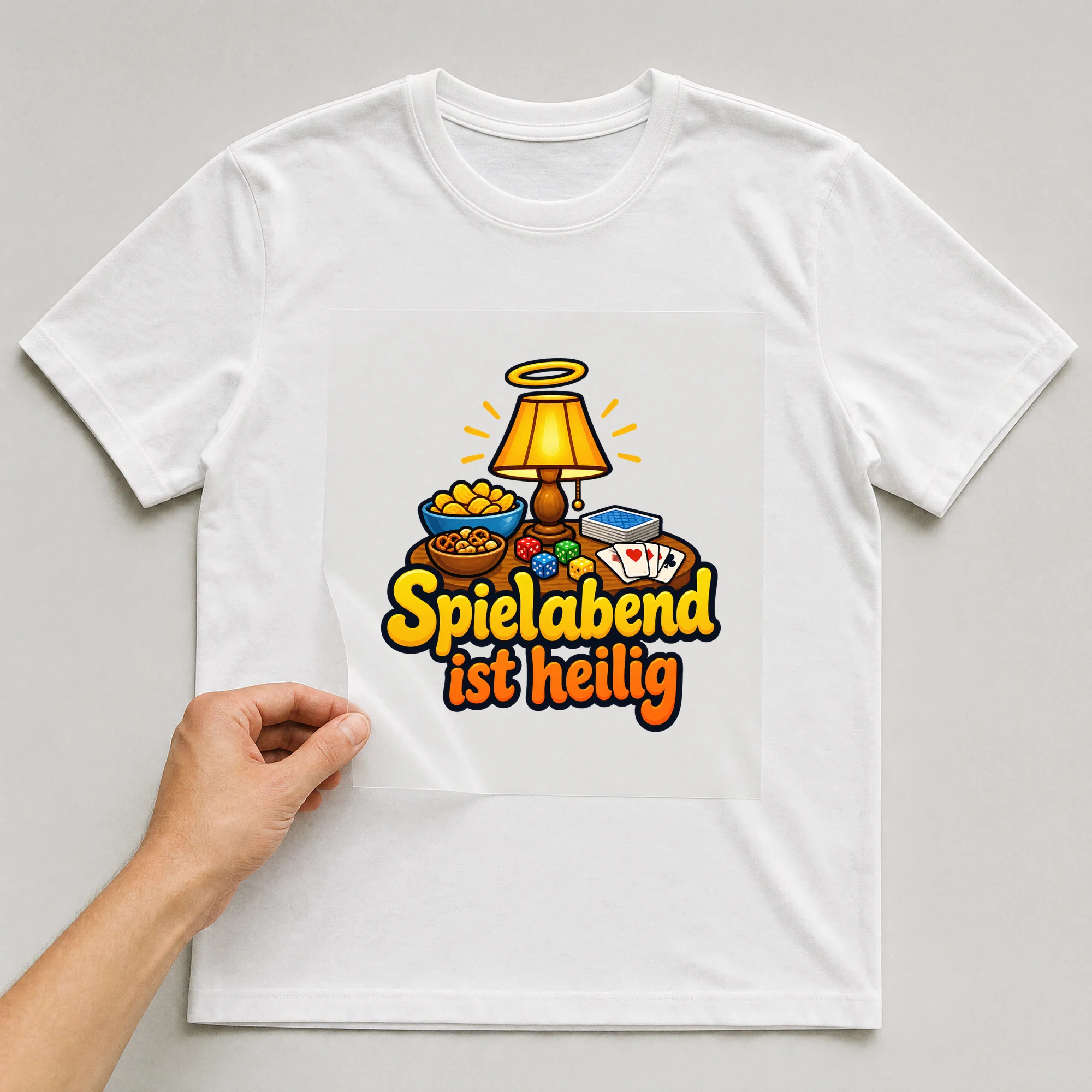 Bügelbild „Spielabend ist heilig“ auf weißem T-Shirt, Folie wird aufgelegt