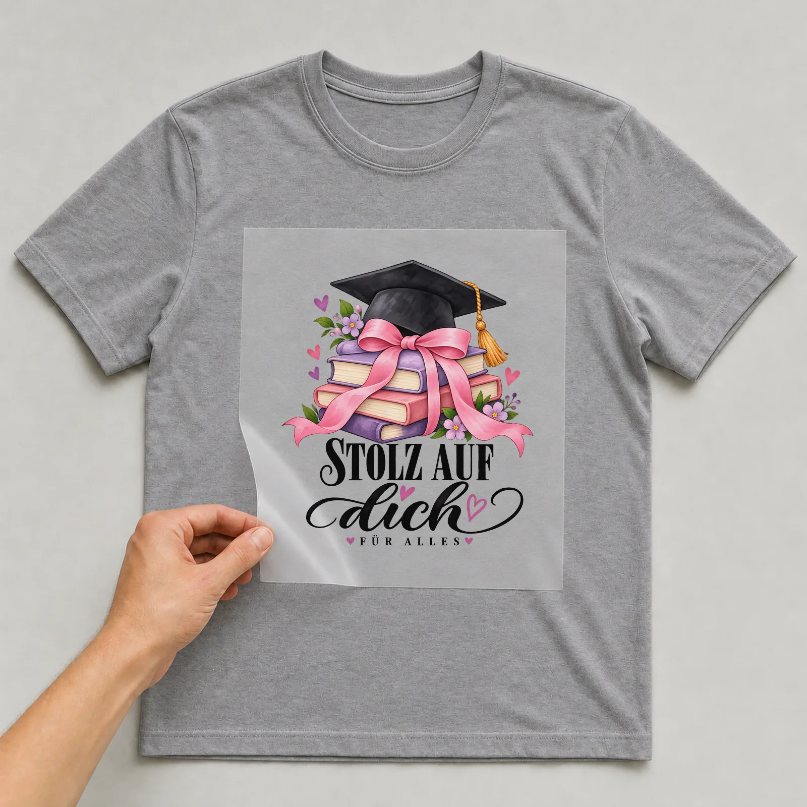 Bügelbild „Stolz auf dich. Für alles“ auf grauem T-Shirt, Folie wird aufgelegt