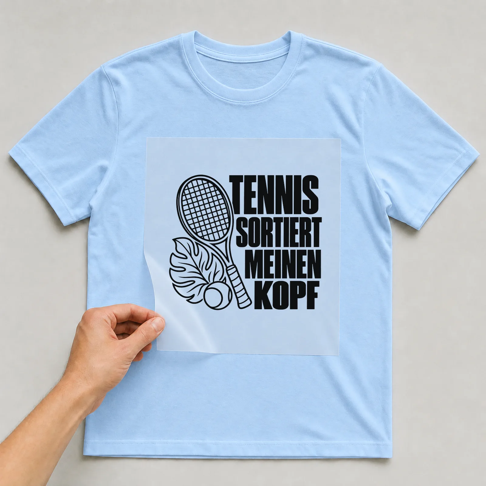 Bügelbild „Tennis sortiert meinen Kopf“ auf hellblauem T-Shirt, Folie wird aufgelegt