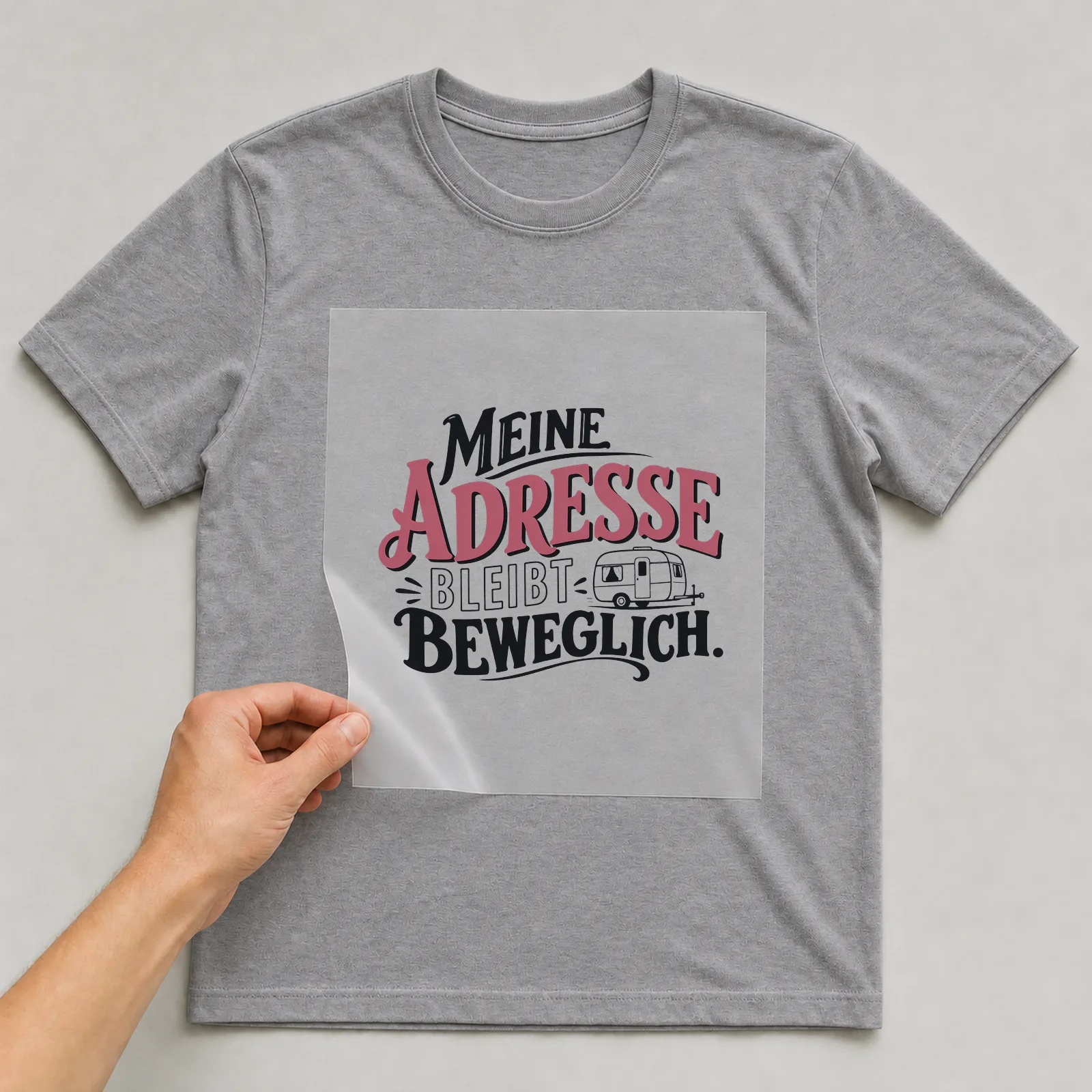 Bügelbild „Meine Adresse bleibt beweglich“ auf grauem T-Shirt, Folie wird aufgelegt