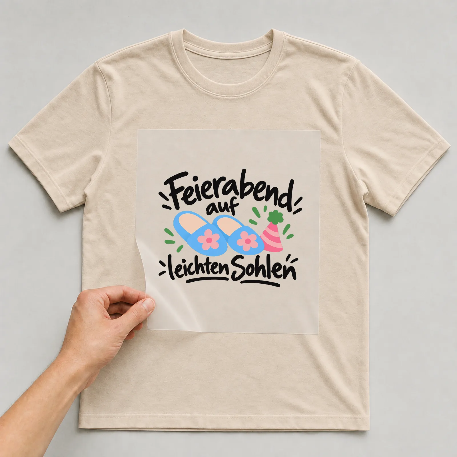 Bügelbild „Feierabend auf leichten Sohlen“ auf beigem T-Shirt, Folie wird aufgelegt